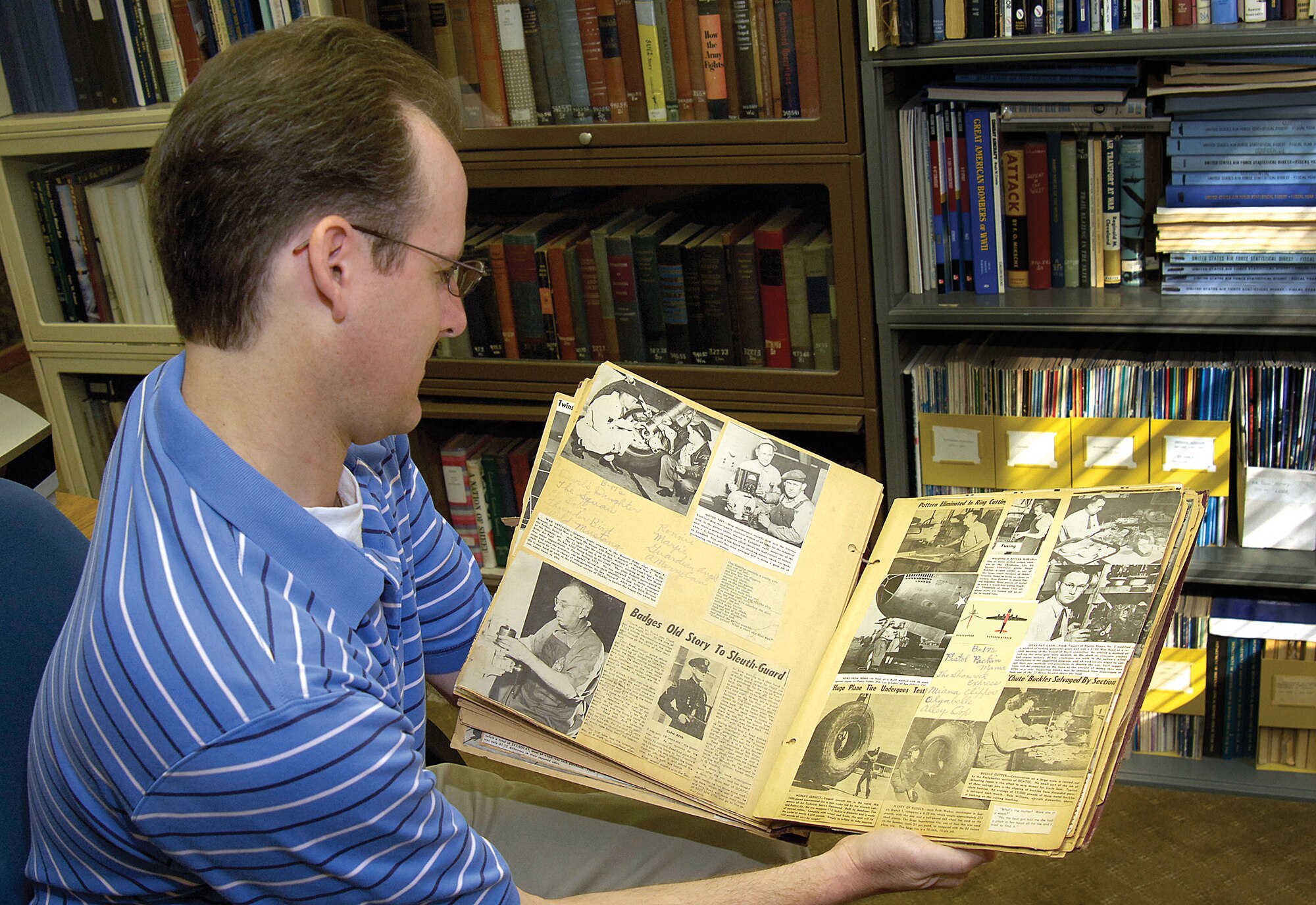 Chris Wright, an archivist in Tinker’s History Office, carefully looks through a recently donated scrapbook of 1940s Oklahoma City newspaper and Tinker Take Off clippings, and a 1942 manual for a “JAHCO” aircraft engine starter. The book was compiled by a woman who worked here at that time in the Maintenance Division.(Air Force photo/Margo Wright)