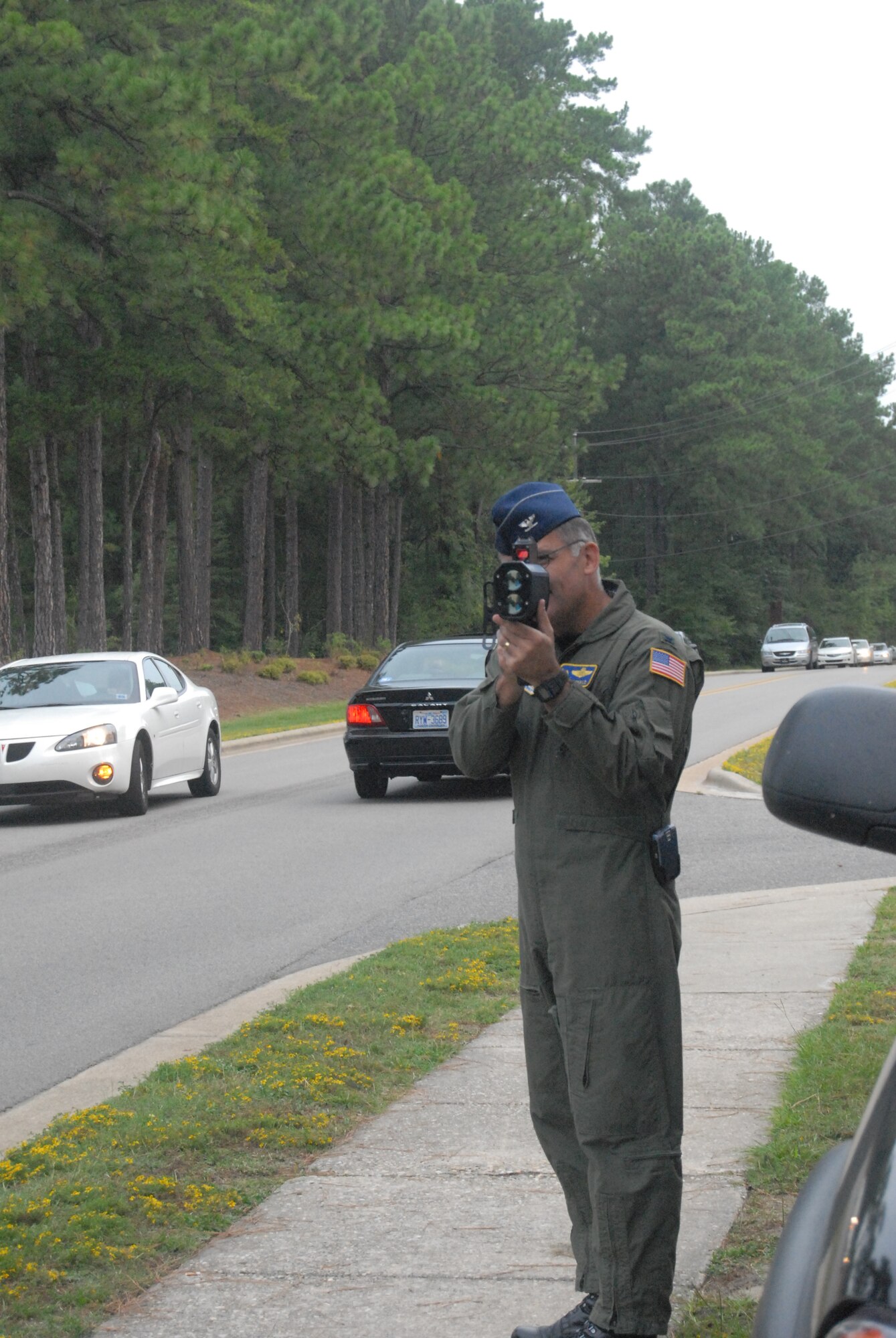 Col. John McDonald, 43rd Airlift Wing Commander, uses the radar gun outside Pope Elementary School before the students started their first day of classes Monday. He was shown how to use the radar gun by Maj. James Hodges, 43rd Security Forces Squadron Commander, who was out there as a reminder to people to slow down in order to prevent accidents or injuries. (U.S. Air Force Photo by Master Sgt. Vicki Johnson)