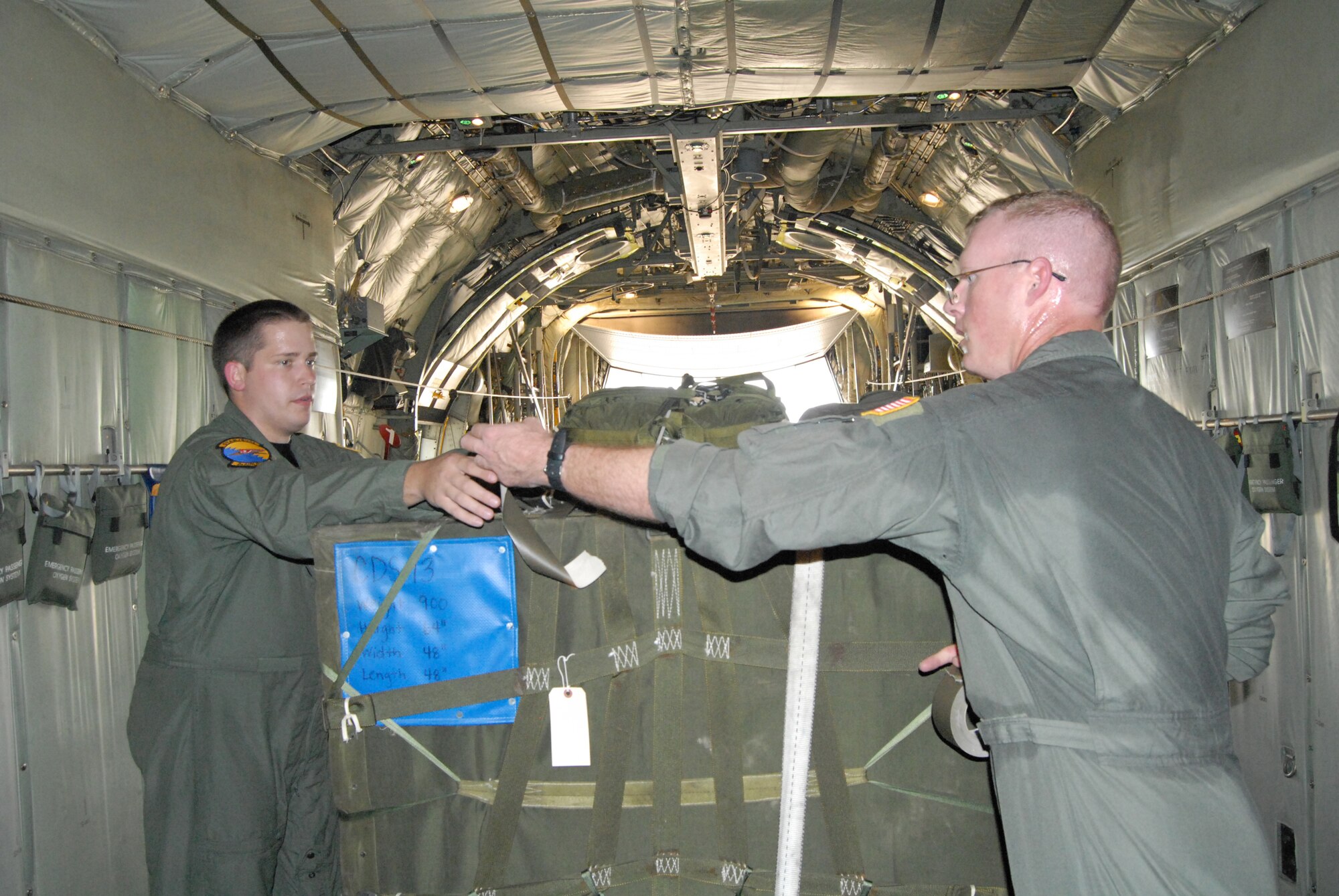 Staff Sgt. Casey Crew and Tech. Sgt. James Segalla, both 2nd Airlift Squadron loadmasters, secure a Container Deliver System bundle onto a C-130H aircraft in preparation for an air drop during a training flight Aug. 21. (U.S. Air Force Photo by Airman 1st Class Mindy Bloem)