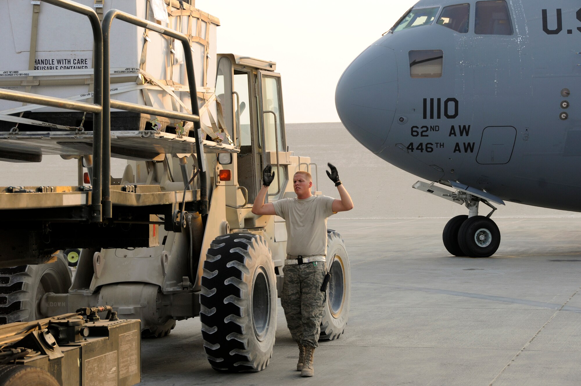 Senior Airman Brett Villar, 8th Expeditionary Air Mobility Squadron, marshals a pallet-laden forklift to a 60K loader Aug. 27, 2008 at an undisclosed air base in Southwest Asia.   Loading a single pallet onto the loader from the forklift is quicker than waiting for the loader to move out of the way, then moving the forklift into position and loading directly into the C-17 Globemaster III.  Airman Villar, a native of Saint Amant, La., is deployed from Charleston Air Force Base, S.C., in support of Operations Iraqi and Enduring Freedom and Joint Task Force-Horn of Africa.  (U.S. Air Force photo by Tech. Sgt. Michael Boquette/Released)
