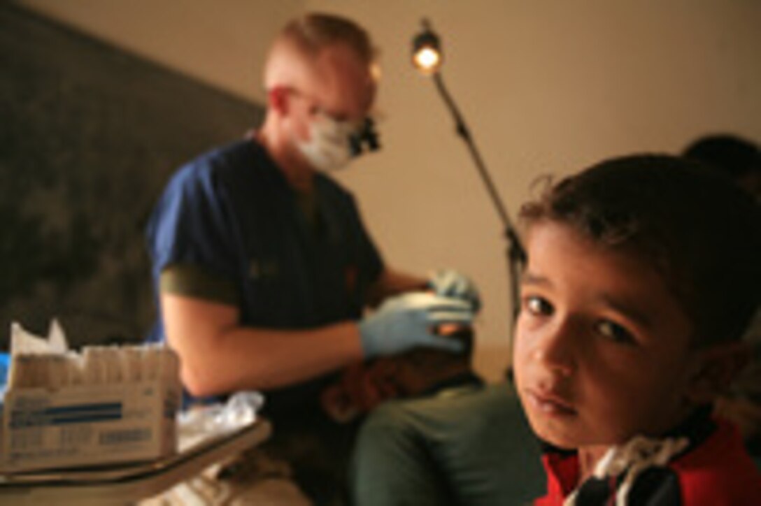 KABANI, Iraq (August 29, 2008) – An Iraqi boy waits for his father to finish an examination during the first Cooperative Dental Engagement here, Aug. 29. Cmdr. Scott Kooistra, dental detachment officer in charge for Dental Platoon, Medical Company, 1st Supply Battalion (-) (Reinforced), worked with Iraqi Army 2nd Lt. Ashraf Ali, a dentist with 7th Iraqi Army Division, to examine more than 100 patients during the CDE. (Photo by Cpl. Tyler B. Barstow)