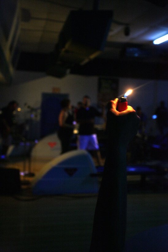 A fan raises a lighter during a ballad performed by Deep 6, a recently created band consisting of eight Marines and civilians, at their first performance in a local bowling alley Aug. 29.  The members of the band are all somehow related to the Marine Corps and got together in August through mutual friends just to have some fun.