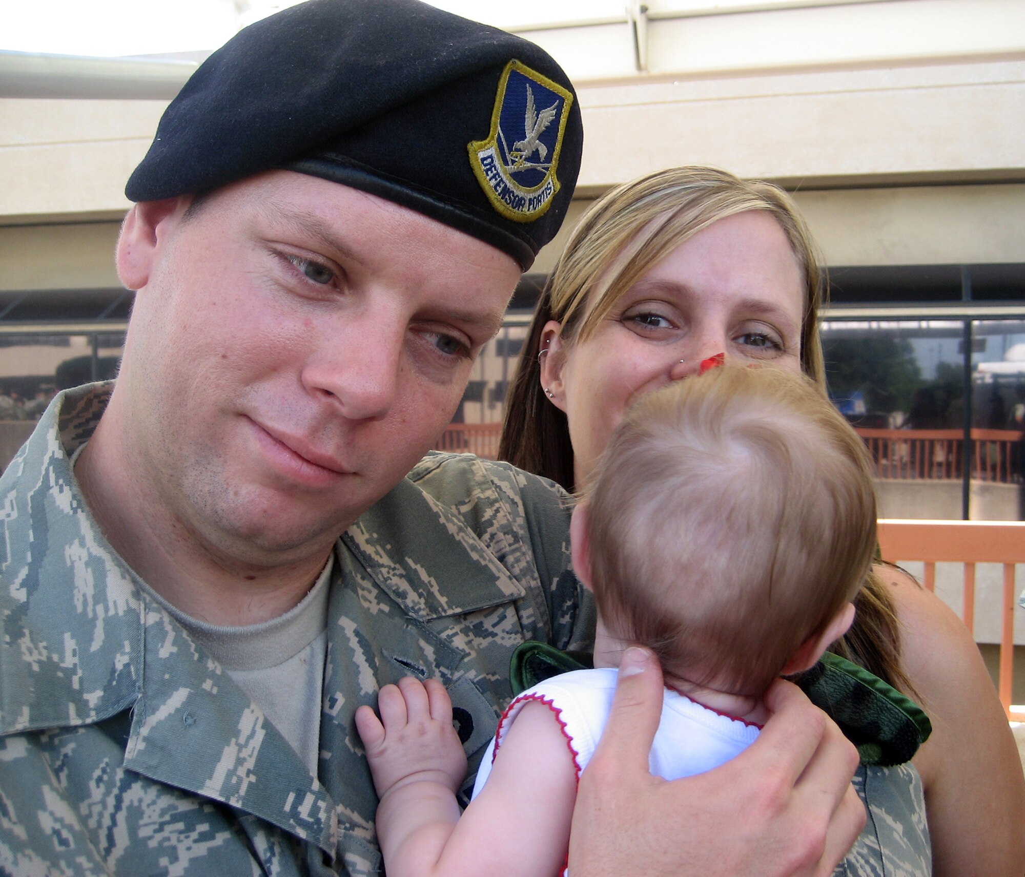 301st Security Forces Squadron member, stationed at Naval Air Station Fort Worth Joint Reserve Base Carswell Field, Texas, embrases his daughter for the first time after returning from a year-long deployment in support of Operation Iraqi Freedom as his wife looks on. (U.S. Air Force Photo)