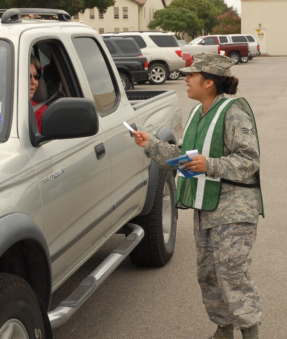 Senior Airman Pauline Flores, Air Force Personnel Center, hands a "Thank You For Wearing Your Seatbelt" card to a person leaving for lunch Aug. 29 at the AFPC complex. Officials stressed safety for the Labor Day weekend by handing out thank you cards and coupons to the base exchange to personnel who were buckled up. (U.S. Air Force photo by Staff Sgt. Tim Bazar)