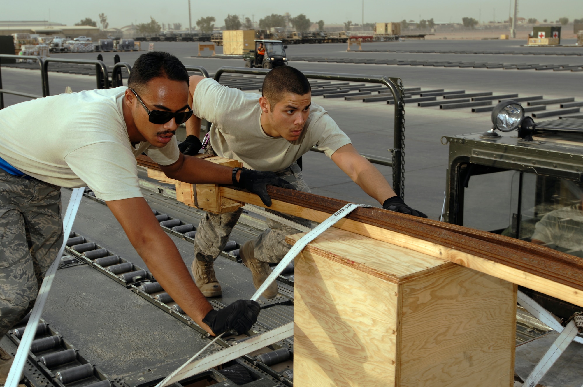 JOINT BASE BALAD, Iraq -- Airmen 1st Class Shane Costa (left) and Dennis Gaxiola, push a palette train off a 60k-loader driven by Senior Airman Derek Dumlao onto a high line dock here Aug. 24. All three Airmen completed a new Air Force Reserve seasoning training program prior to deploying here. The program allows Airmen to voluntarily remain on active duty for upgrade training, finishing it in three months instead of 14 to 16 months. Dumlao, Gaxiola and Costa, aerial porters with the 332nd Expeditionary Logistics Readiness Squadron here, are deployed from the 624th Regional Support Group at Hickam Air Force Base, Hawaii. All three Airmen graduated from Leilehua High School in Wahiawa, Hawaii, in 2004. (U.S. Air Force photo/Airman 1st Class Jason Epley)