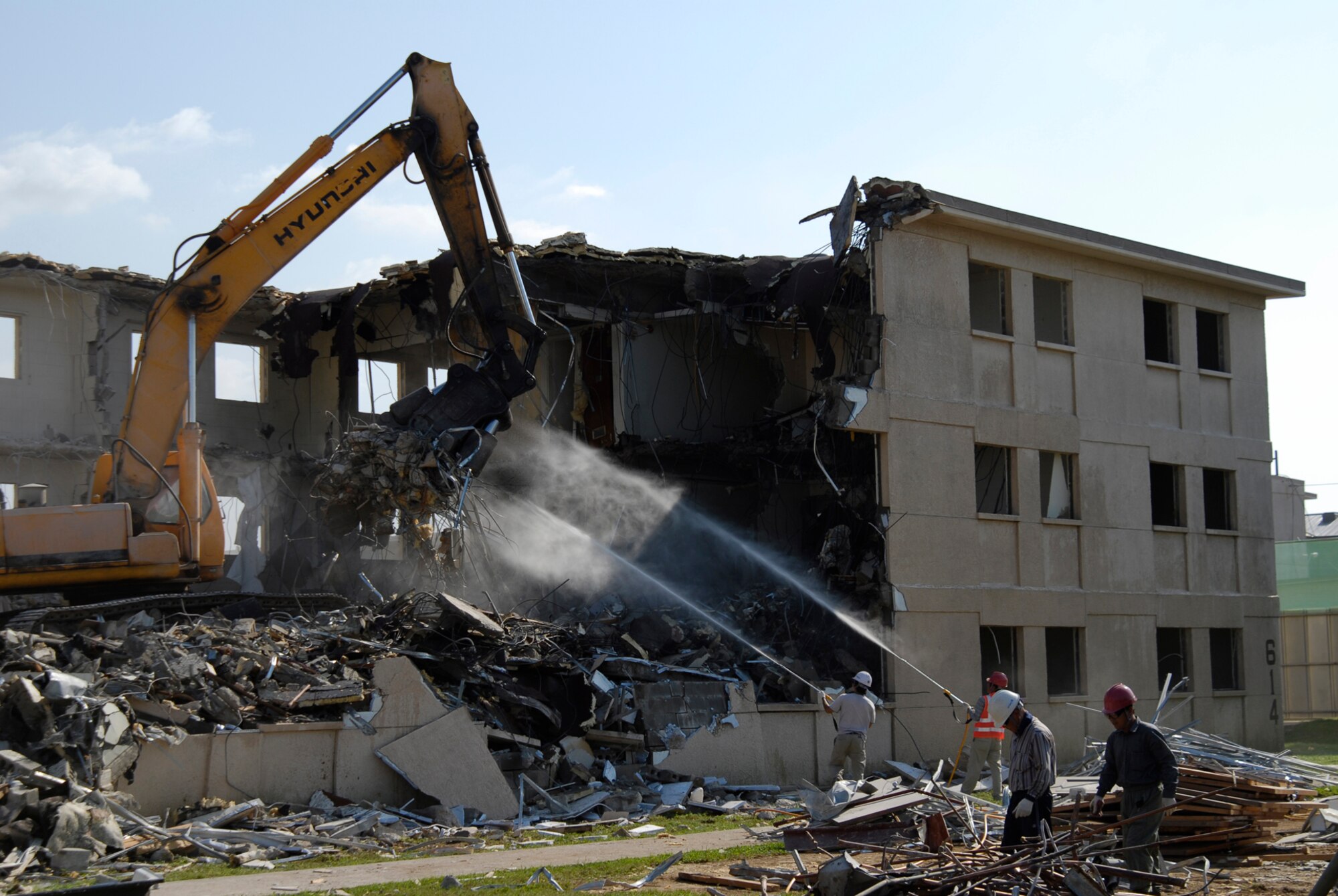 With two brand new, multi-story dormitories open, workers tear down and dispose of building 614 at Kunsan Air Base. The demolition is a part of a base wide quality of life improvement initiative to include construction of new dormitories. (U.S. Air Force photo/Staff Sgt. Jason Colbert)