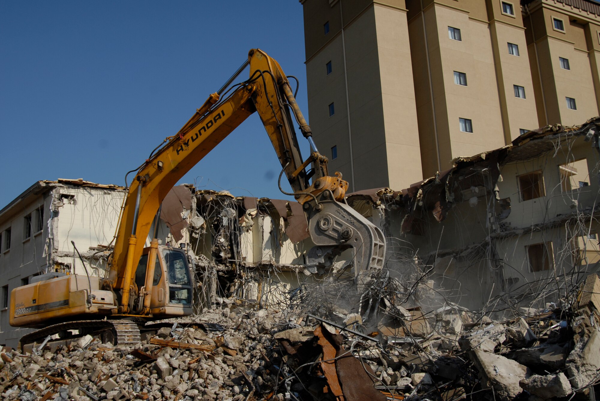 With two brand new, multi-story dormitories open, workers tear down and dispose of building 614 at Kunsan Air Base. The demolition is a part of a base wide quality of life improvement initiative to include construction of new dormitories. (U.S. Air Force photo/Staff Sgt. Jason Colbert)