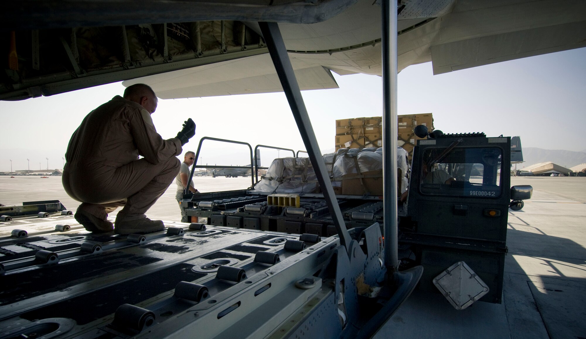 BAGRAM AIR FIELD, Afghanistan -- A loadmaster guides a Tunner 60K loader towards a C-130J Hercules here on August 28, 2008. The loader has motorized wheels and rollers to allow loadmasters to rapidly transfer cargo into the aircraft. (U.S. Air Force photo by Staff Sgt. Samuel Morse/Released)