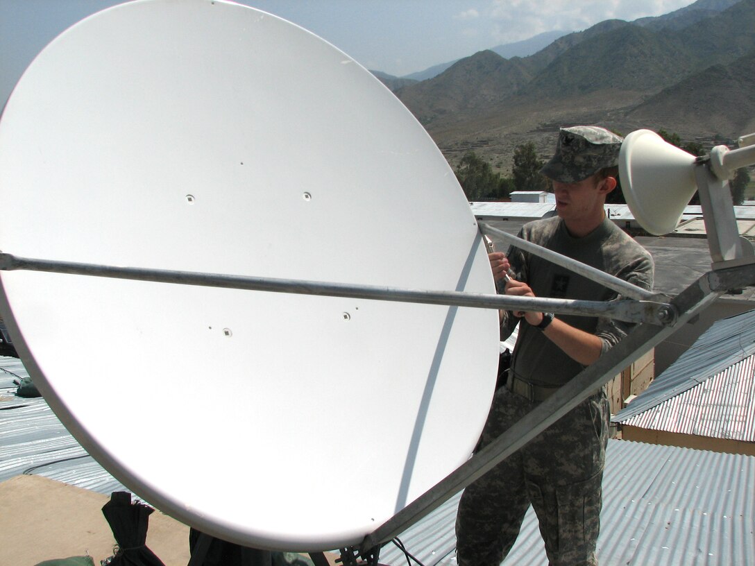 Navy Petty Officer 3rd Class Shawn Simmons, a ship’s serviceman from Sherman, Texas, stationed onboard the USS Kauffman in Norfolk, Va., installs a new cable on a satellite dish at Camp Wright, Afghanistan, Aug. 26, 2008. Courtesy photo  