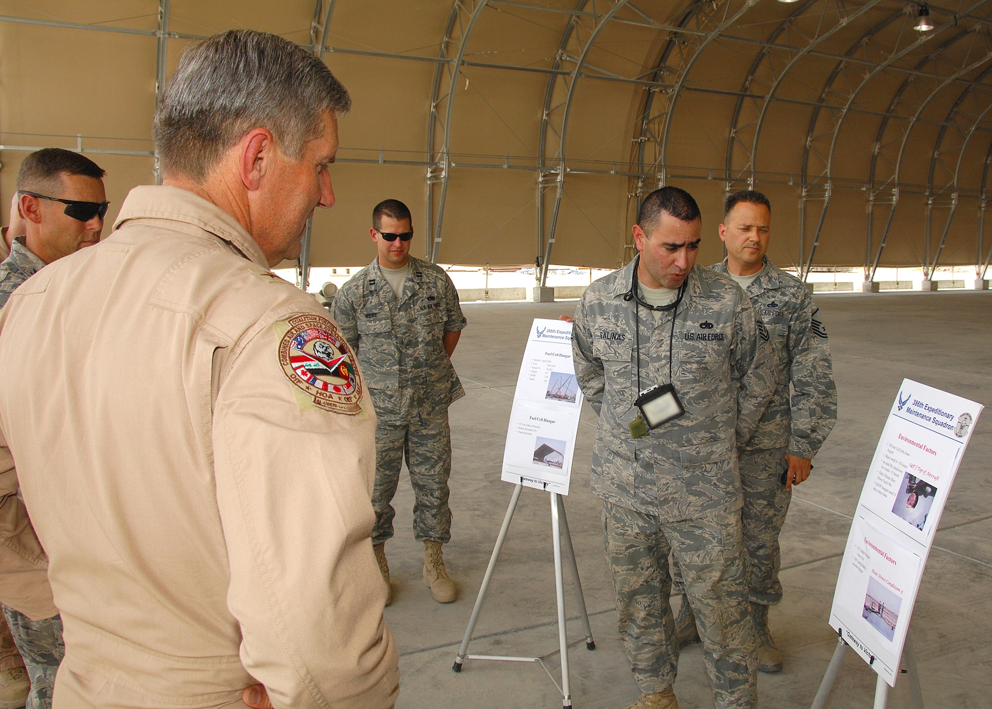 SOUTHWEST ASIA -- Brig. Gen. Lance Undjem, Combined Air and Space Operations Center director, listens to a briefing by Tech. Sgt. Benedict Salinas, 386th Expeditionary Maintenance Squadron, on Aug. 29 at an airbase in Southwest Asia. The brief, which discussed the 386th Air Expeditionary Wing's newly completed fuel cell building, explained the overall efficiency improvements in fuel tank cleaning that will result from its operation. General Undjem is the new CAOC director, and is touring U.S. Central Command observing how the CAOC contributes to day-to-day operations in the theater. Sergeant Salinas is deployed from Dyess Air Force Base, Texas. (U.S. Air Force photo/Tech. Sgt. Raheem Moore)
