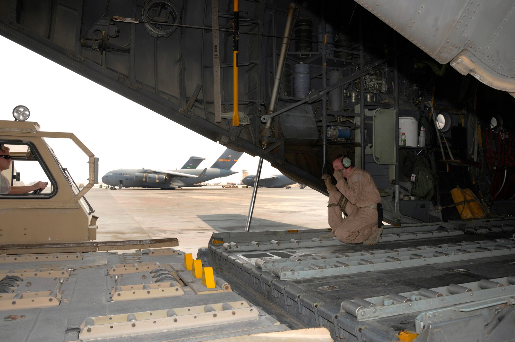 Airman 1st Class David Smallsreed, 746th Expeditionary Airlift Squadron, motions with both hands while giving directions to Staff Sgt. Jeremy Kelley, 8th Expeditionary Air Mobility Squadron 60K loader operator Aug. 28, 2008, at an undisclosed air base in Southwest Asia.  Two pallets of equipment and supplies are to be loaded onto the C-130 Hercules aircraft.  Airman Smallsreed is a native of Braceville, Ohio, and deployed from Yokota Air Base, Japan. Sergeant Kelley hails from Amsterdam, N.Y., and is deployed from Charleston Air Force Base, S.C. Both are deployed in support of Operations Iraqi and Enduring Freedom and Joint Task Force-Horn of Africa.  (U.S. Air Force photo by Tech. Sgt. Michael Boquette/Released)