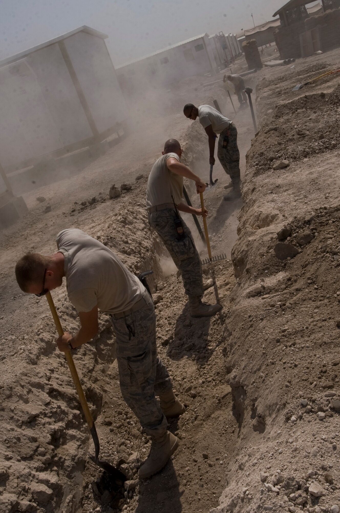 ALI BASE, Iraq -- Airmen of the 407th Expeditionary Civil Engineer Squadron, dig a trench for a sewer and water line Aug. 15, 2008. In the transition from tents to trailers, the 407th ECES is rerouting the power supply along with laying water and sewage systems for latrines used by all Airmen here. (U.S. Air Force photo/Airman 1st Class Christopher Griffin)