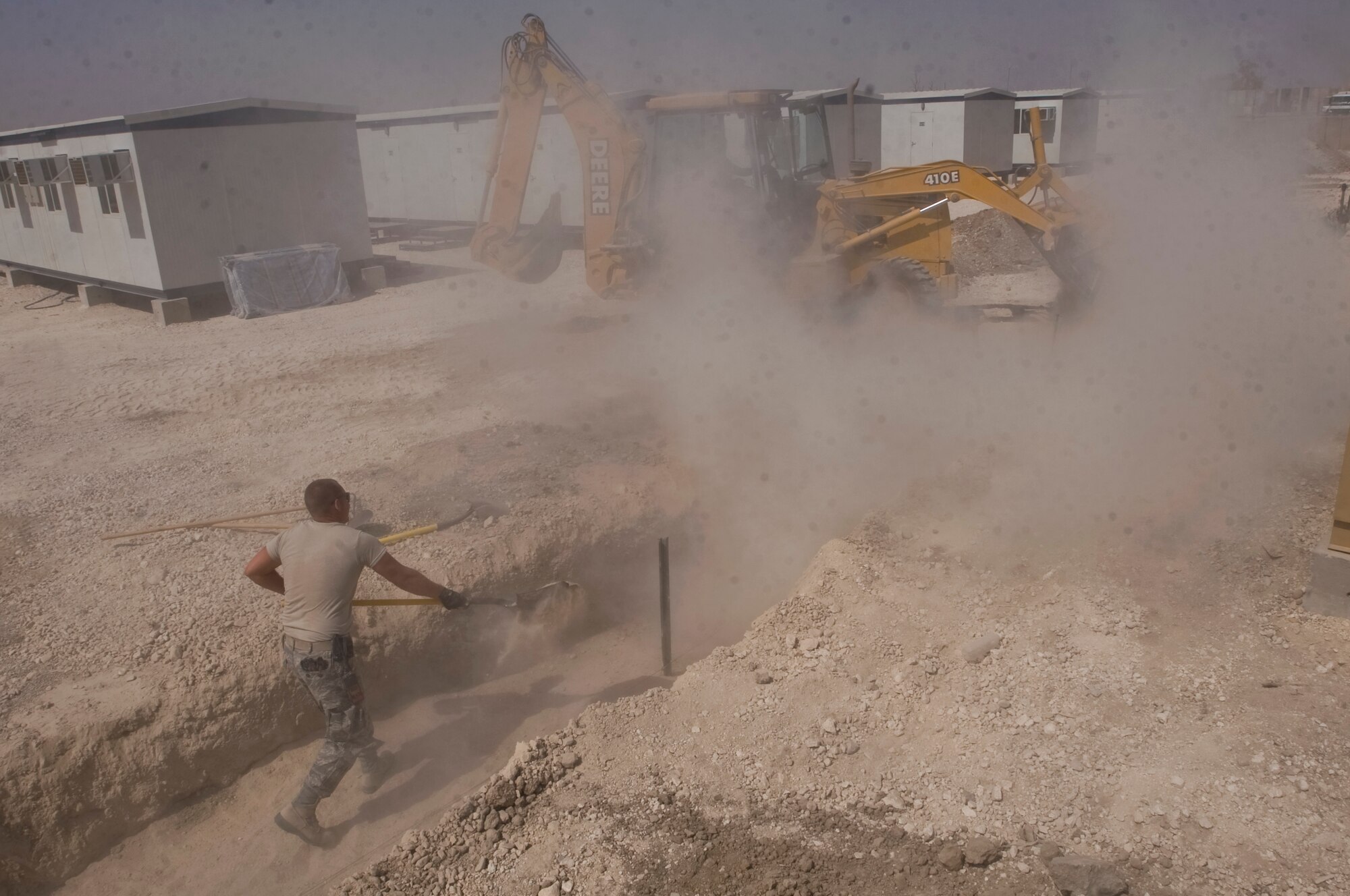 ALI BASE, Iraq -- Staff Sgt. Trevor Petersma, 407th Expeditionary Civil Engineer Squadron utilities systems craftsman, levels sand as it is poured in a trench Aug. 15, 2008. In the transition from tents to trailers, the 407th ECES is rerouting the power supply along with laying water and sewage systems for latrines used by all Airmen here. Petersma is deployed from Malmstrom Air Force Base, Mont.(U.S. Air Force photo/Airman 1st Class Christopher Griffin)