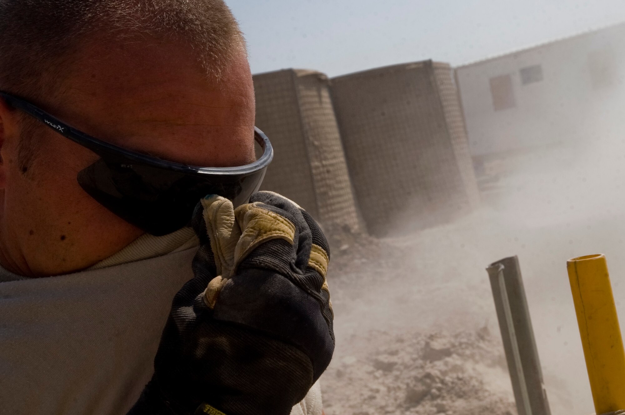 ALI BASE, Iraq -- Staff Sgt. Trevor Petersma, 407th Expeditionary Civil Engineer Squadron utilities systems craftsman, masks his face from sand as it is poured in a trench Aug. 15, 2008. In the transition from tents to trailers, the 407th ECES is rerouting the power supply along with laying water and sewage systems for latrines used by all Airmen here. Petersma is deployed from Malmstrom Air Force Base, Mont. (U.S. Air Force photo/Airman 1st Class Christopher Griffin)