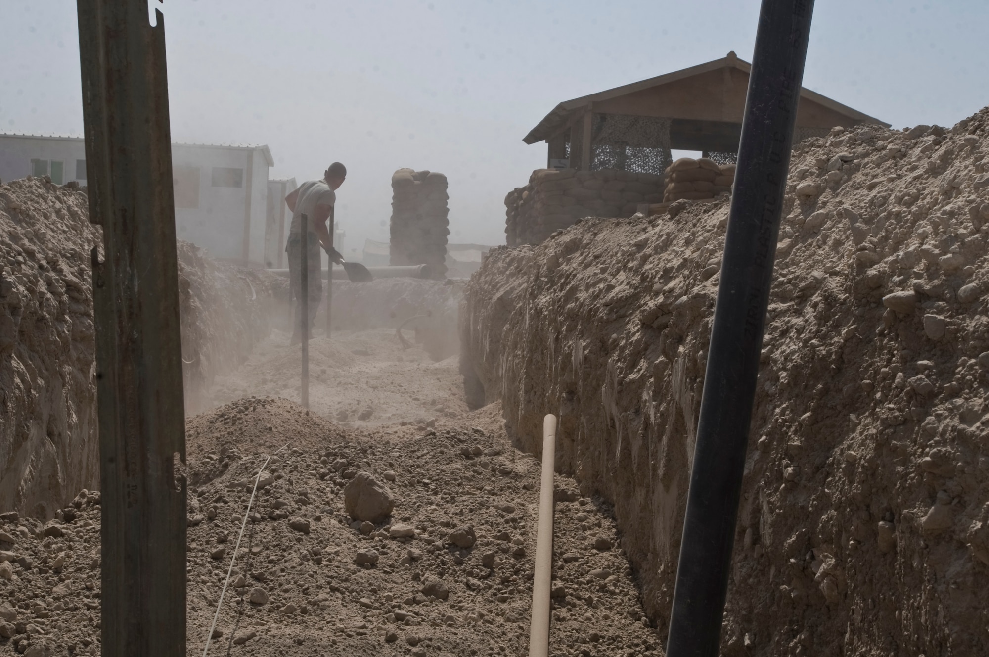 ALI BASE, Iraq -- Staff Sgt. Trevor Petersma, 407th Expeditionary Civil Engineer Squadron utilities systems craftsman, levels sand as it is poured in a trench Aug. 15, 2008. In the transition from tents to trailers, the 407th ECES is rerouting the power supply along with laying water and sewage systems for latrines used by all Airmen here. Petersma is deployed from Malmstrom Air Force Base, Mont. (U.S. Air Force photo/Airman 1st Class Christopher Griffin)