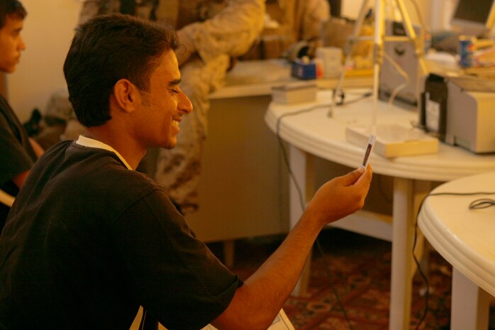 FALLUJAH, Iraq (Aug. 30, 2008) – A local Iraqi receives his new identification and laughs at the photo he took during a remote badging operation here, Aug. 30. Company I, 3rd Battalion, 6th Marines and Iraqi Police in the Shuhada District of Fallujah held the badge drive to serve more than 100 citizens with outdated identifications. Residents need a badge to enter the city and take advantage of employment opportunities. (Official U.S. Marine Corps photo by Cpl. Chris Lyttle) (RELEASED)