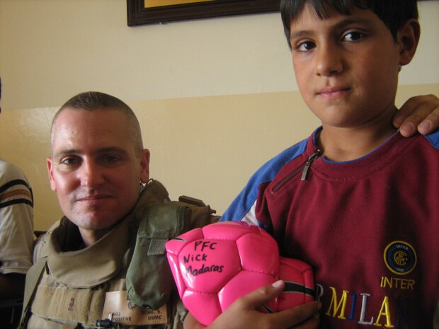 Chief Warrant Officer Shane M. Duhe, a civil affairs team leader, Detachment 3, Team 5, Regimental Combat Team 1, hands out a soccer ball to a young Iraqi child during a civil affairs operation in Fallujah, Iraq, Sept. 5. The soccer ball contains the name of PFC Nick A. Madaras, an Army soldier who was killed while conducting combat operations in Iraq. The soccer balls represent a goal Madaras had to pass out soccer balls to the children of Iraq.