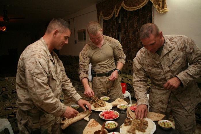 From left to right, Capt. Derek Nielson, Capt. Seth MacCutcheon and Maj. Marcus Mainz, all with 3rd Battalion, 7th Marine Regiment, Regimental Combat Team 5, help themselves to an Iraqi dinner in Hit, Iraq, Sept. 2. Marines with Company L, 3rd Bn., 4th Marine Regiment, introduced the Marines from the incoming battalion to one of the sheiks in the area. At the meeting, the sheik had dinner made for the Marines and discussed the progress that has been made in the area.::r::::n::