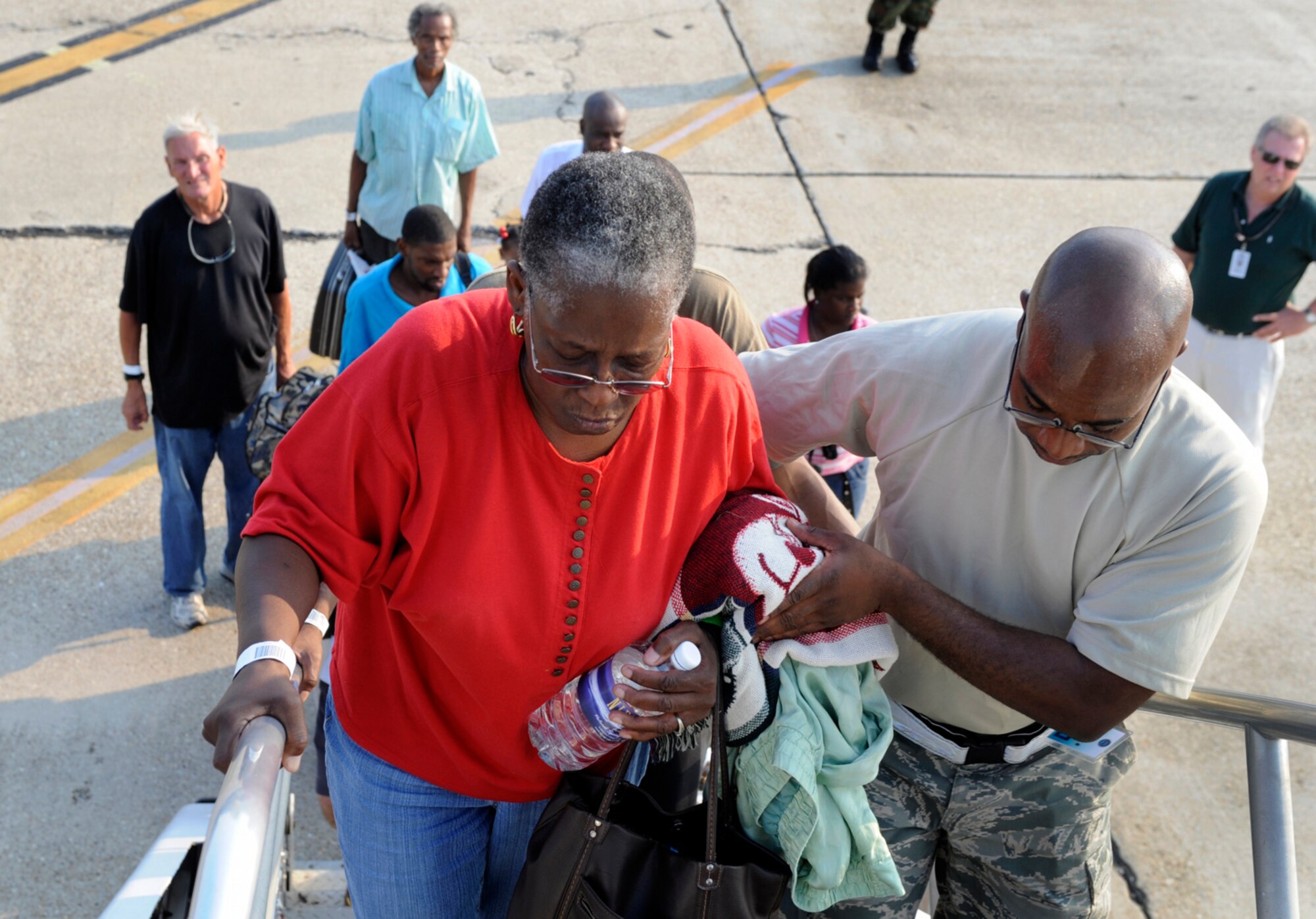 Tech. Sgt. Cedric Scott assists an evacuee leaving before Hurricane Gustav hits the Gulf Coast as she boards a flight at the Louis Armstrong International Airport in New Orleans Aug. 30.  Officials with the Federal Emergency Management Agency and Department of Defense have chartered aircraft to transport evacuees to destinations safely outside the path of the hurricane.  Sergeant Scott is from the 615th Contingency Response Wing at Travis Air Force Base, Calif.  (U.S. Air Force photo/Staff Sgt. Shawn Weismiller)