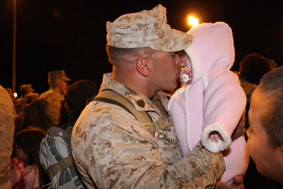 Gunnery Sgt. Jose E. Caraballo, a platoon sergeant with Headquarters and Service Company, 2nd Battalion, 7th Marine Regiment, says hello to his daughter for the first time during his homecoming Nov. 30 at the Combat Center’s Victory Field. Friends and family braved cold temperatures and late hours, but spirits were high and the warfighters of 2/7, who deployed from the Combat Center in support of Operation Enduring Freedom in March and April, were greeted with loud applause, hugs, and kisses. The Combat Center welcomed back more Marines and sailors from 2/7, when warfighters from Company G and Headquarters and Service Company arrived at Victory Field Thursday morning.  ::r::::n::