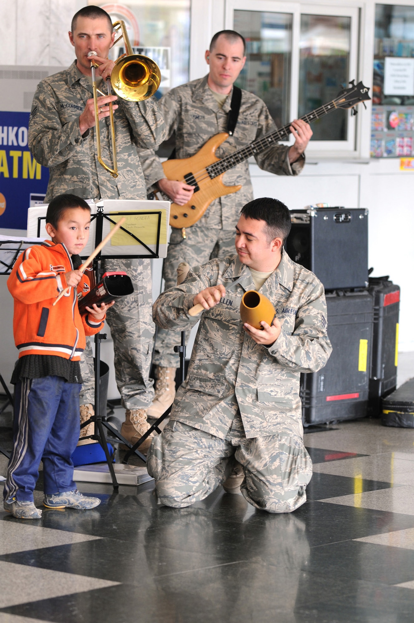 MANAS AIR BASE, Kyrgyzstan -- A Kyrgyz child plays the cow bell during a performance by the Air Forces Central band Sonora at the Manas International Airport, Nov. 13. Sonora visited Manas AB, Nov. 12-20, and played 11 performances during their stay. Manas serves as the premier air mobility and refueling hub for operations in Afghanistan, providing daily refueling missions and supporting personnel and cargo transiting in and out of Afghanistan. (U.S. Air Force photo/Senior Master Sgt. Patrick J. McCracken)