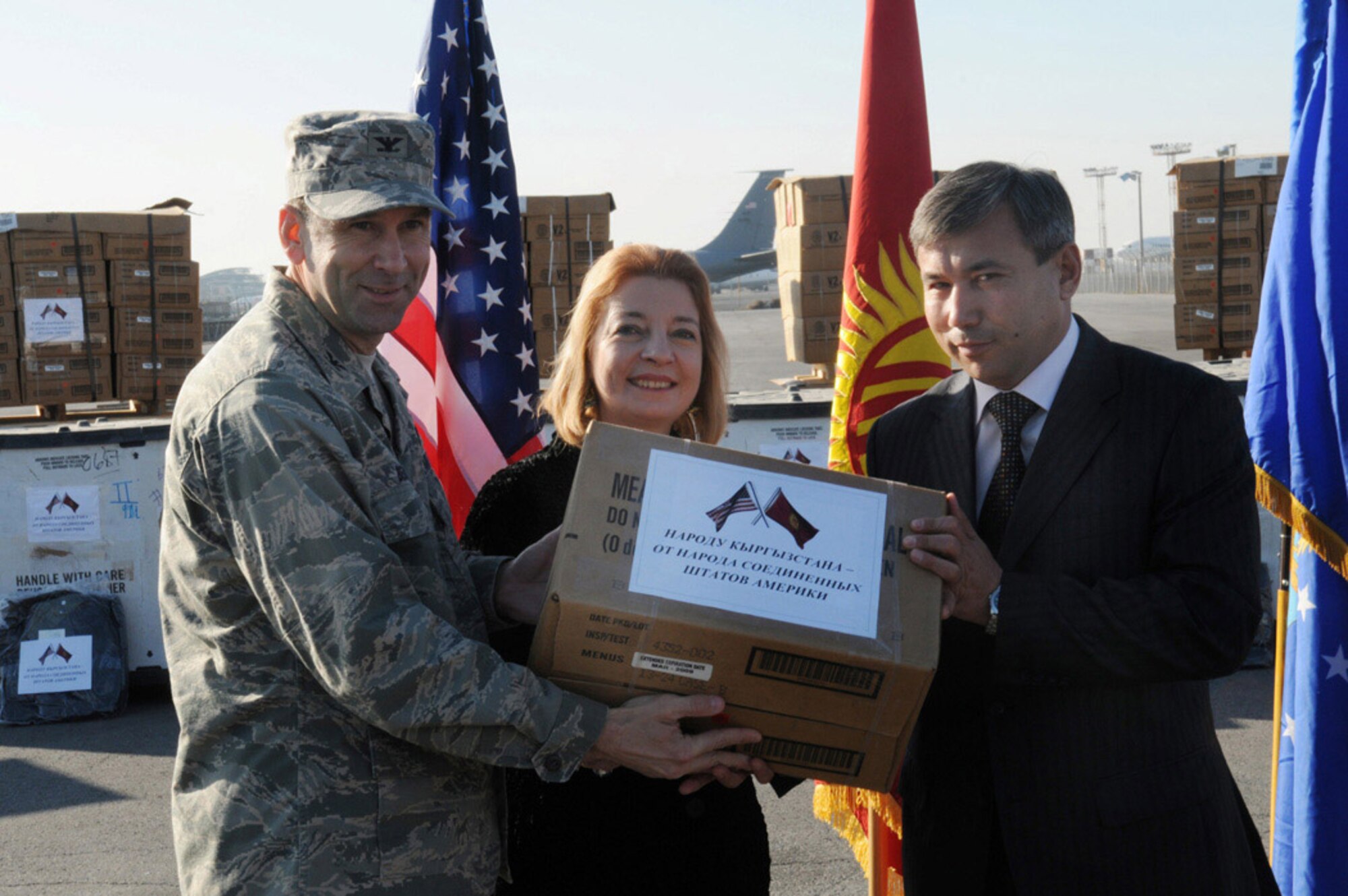 Col. Christopher Bence, 376th Air Expeditionary Wing commander at Manas Air Base, Kyrgyzstan, and Tatiana Gfeoller, U.S. Ambassador to the Kyrgyz Republic, hand the first box of meals-ready-to-eat to Mr. Akyl Aitbaev, deputy minister at the Ministry of Emergency Situations, during a humanitarian assistance ceremony Nov. 25. Department of Defense officials donated MREs and cold weather sleeping bags to help local Kyrgyz who may need assistance during the coming winter. (Air Force photo/Senior Airman Ruth Holcomb)