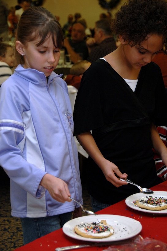 Savanna Mattke and Maya Mobley, daughters of Tech. Sgt. Paul Mattke, decorate cookies at the Dakota's Club before the arrival of Santa Clause.  Entertainment including a magic show, cookie decorating and photos with Santa were provided during the event sponsored by the 28th Force Support Squadron. (U.S. Air Force photo/Senior Airman Anthony Sanchelli)