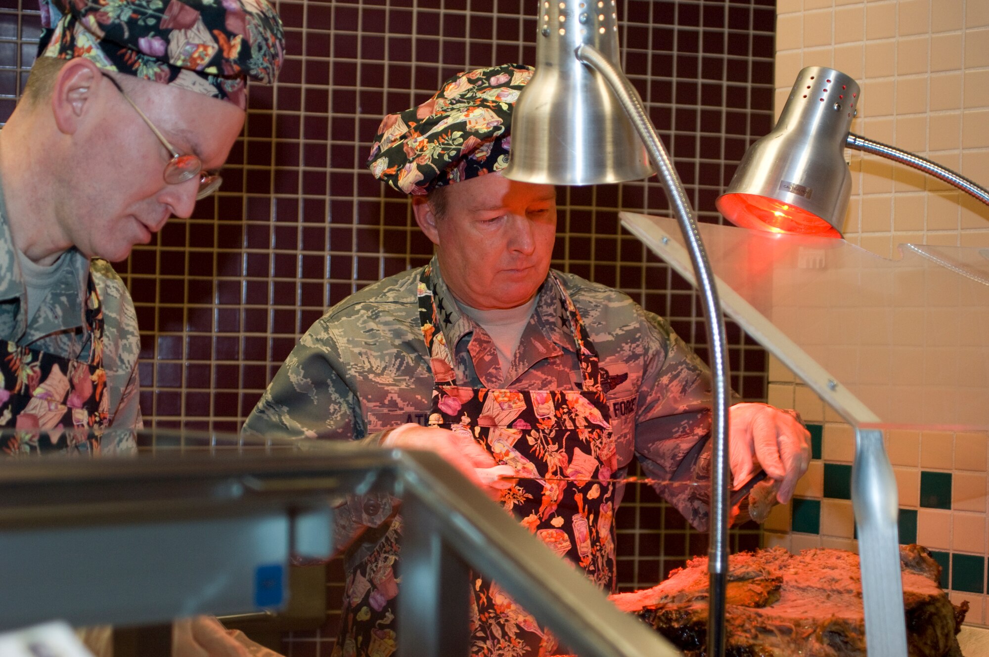 ELMENDORF AIR FORCE BASE, Alaska -- Lt. Gen. Dana Atkins and Chief Master Sgt. Robert Moore, 11th Air Force command chief master sergeant, prepare a plate for a customer at the Iditarod Dining Facility Nov. 27. Several members of Elmendorf leadership served food to the Iditarod customers. General Atkins is the commander, 11th Air Force, Alaskan Command, Alaska NORAD Region, Joint Task Force Alaska. (U.S. Air Force photo/Airman 1st Class David Carbajal)