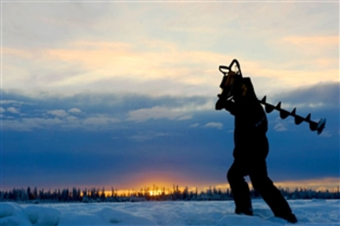 U.S. Air Force Airman 1st Class Caleb Hurley carries an ice auger on the frozen Tanana River during construction of an ice bridge near Fairbanks, Alaska, Nov. 24, 2008. The ice bridge, which is five feet deep, a mile long and capable of supporting more than 110 tons, vanishes in the spring.