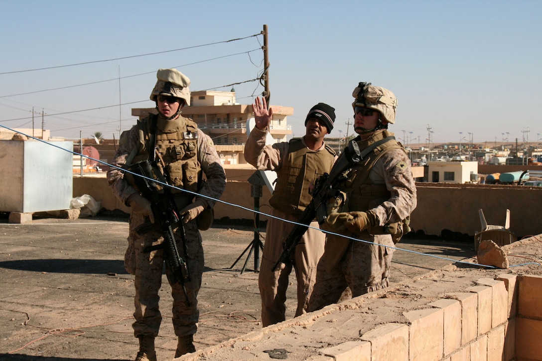 Tamer Talal Hammad, a satellite communications expert and Arabic interpreter from Jordan, assists Lance Cpl. Michael Johnson (left) and Cpl. Martin C. Conroy from Communications Platoon, Headquarters and Service Company, 2nd Battalion, 25th Marine Regiment in conducting a site survey for installation of a radio station antenna on the roof of the Rutbah City Council building in western Iraq, Dec. 2.  The Reserve Marines of 2/25 worked with local Iraqi technicians to set up the first-ever radio station in Rutbah during the month of December.  Official Marine Corps photo by Capt. Paul L. Greenberg