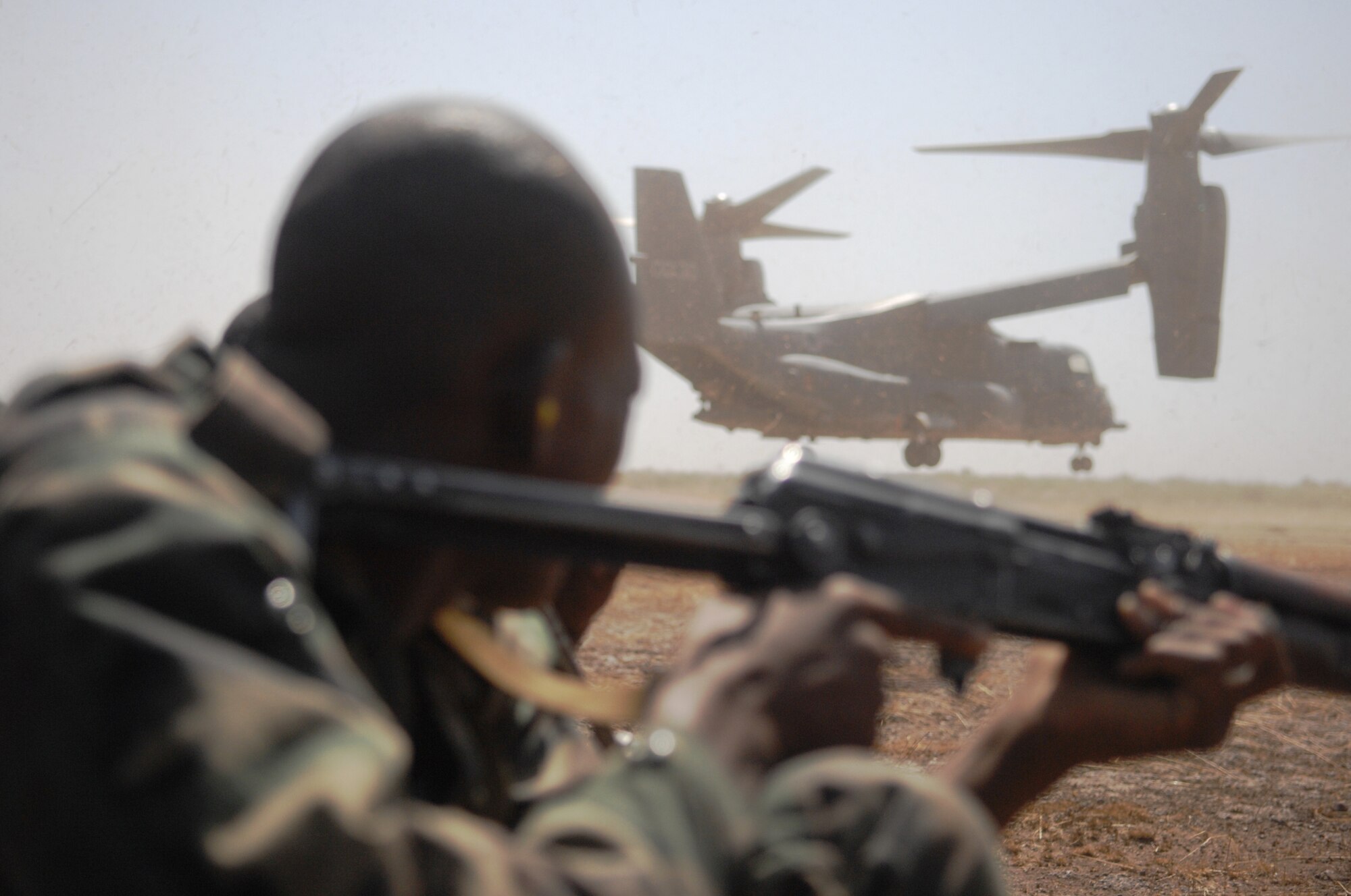 A Malian soldier takes a defensive position while an Air Force Special Operations Command CV-22 Osprey departs a landing zone in Bamako, Mali as part of a drill for Exercise Flintlock. This military exercise is planned and coordinated in collaboration with African and European partner nation military forces to build capacity among Trans-Saharan nations so that they may more effectively address issues which threaten peace, stability and security. (U.S. Air Force photo)