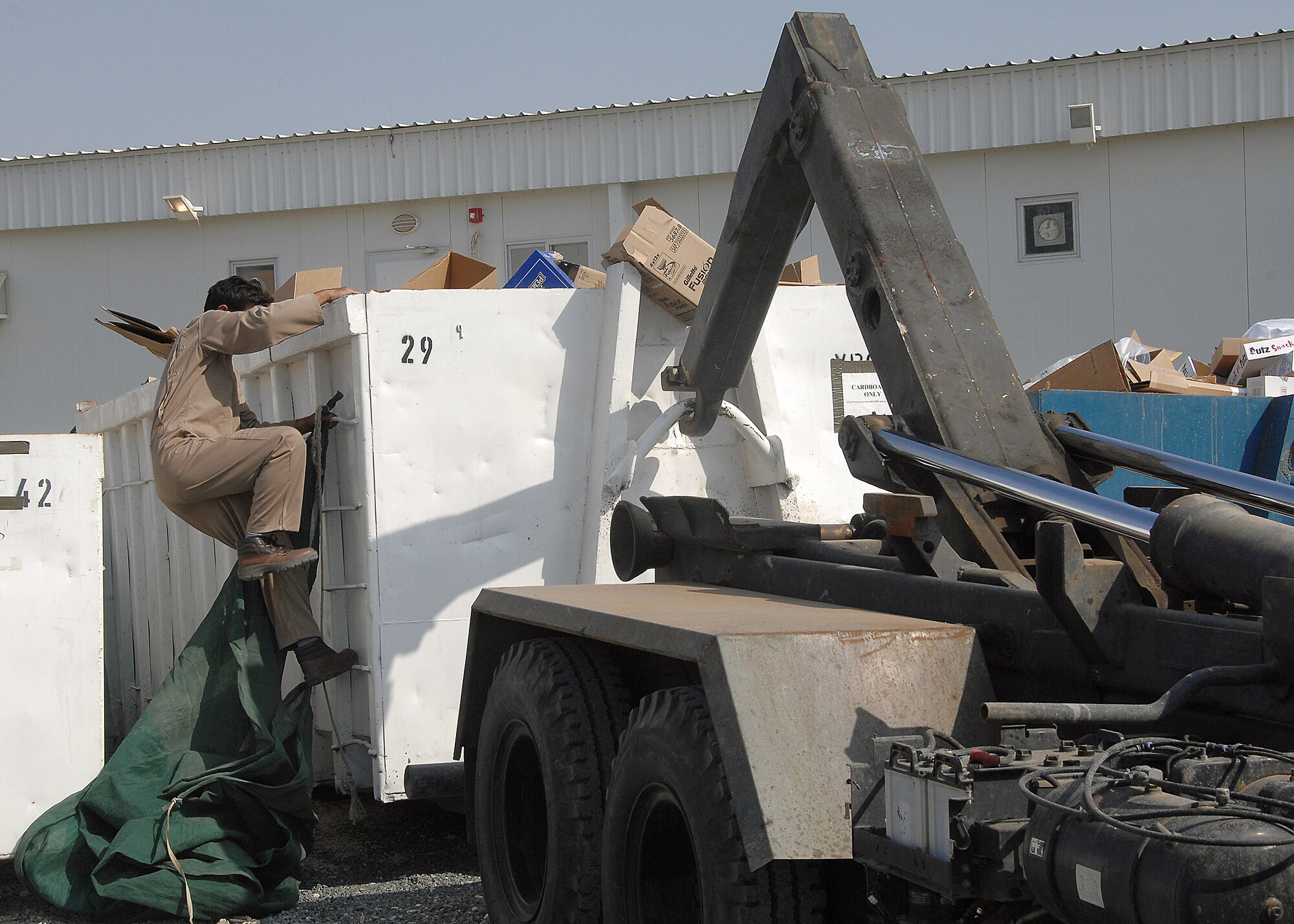 A recycling company worker prepares to cover and haul away a cardboard recycling bin on Nov. 15 at an air base in Southwest Asia. Officials from the 386th Air Expeditionary Wing recycle various items, to include cardboard boxes and plastic bottles. The money that is generated through the recycling program goes back to the base populace for quality of life initiatives and morale, welfare and recreation programs. (U.S. Air Force photo/Tech. Sgt. Raheem Moore) 

