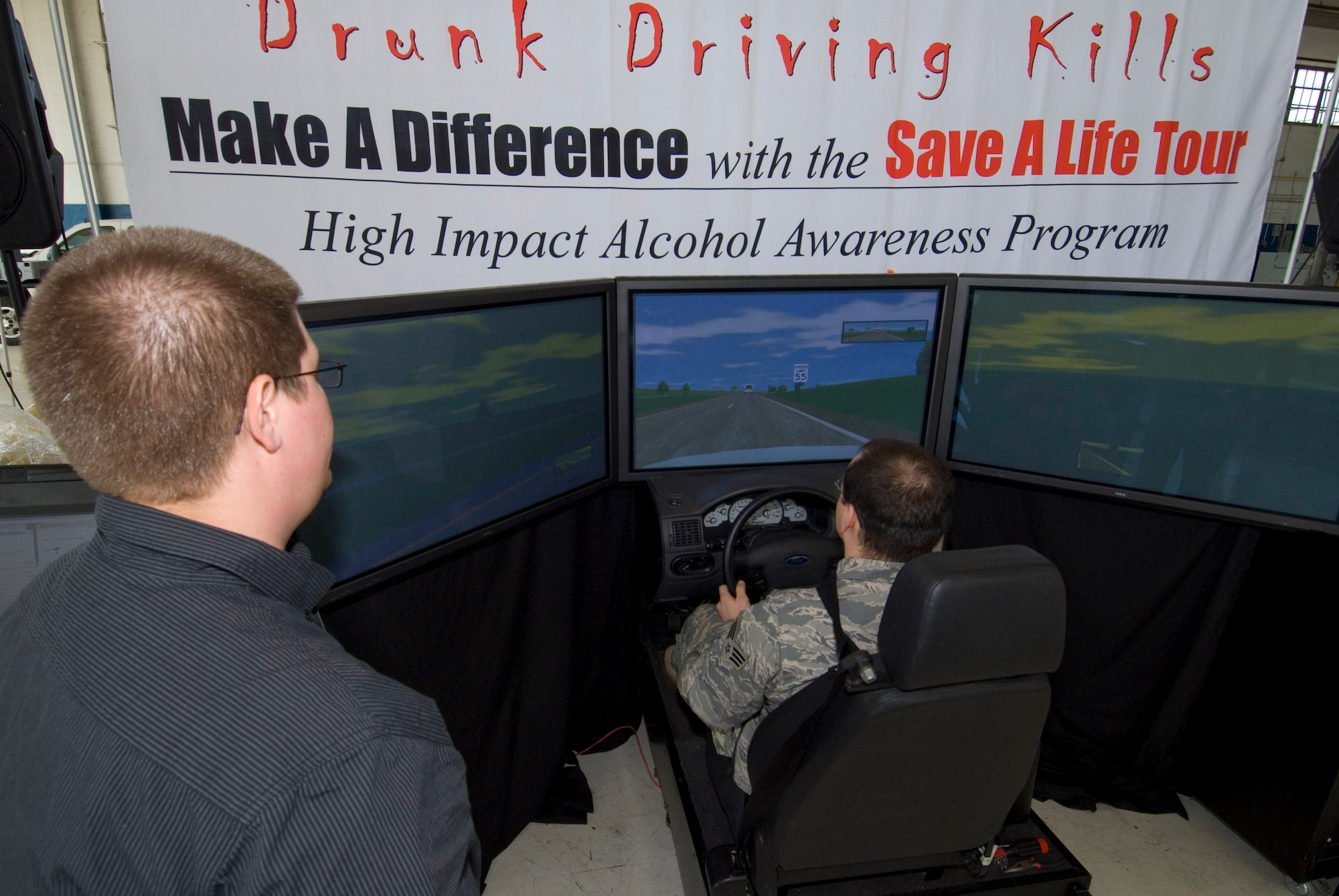 With the guidance of Jordan Brinks, Save A Life Tour simulator instructor, Staff Sgt. Jonathan Early attempts to navigate a driving scenario as if he’s under the influence of alcohol Thursday. The Save a Life Tour began when Mr. Brinks, along with his team, began touring military installations to educate Airmen on the effects of alcohol. (Air Force photo by Jamie Pitcher)
