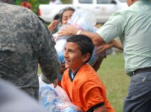 A child hands a bag of food to Army Specialist Ethan Anderson Dec. 1 at a food staging point near Puerta Limon, Costa Rica. (U.S. Air Force photo by Staff Sgt. Joel Mease)