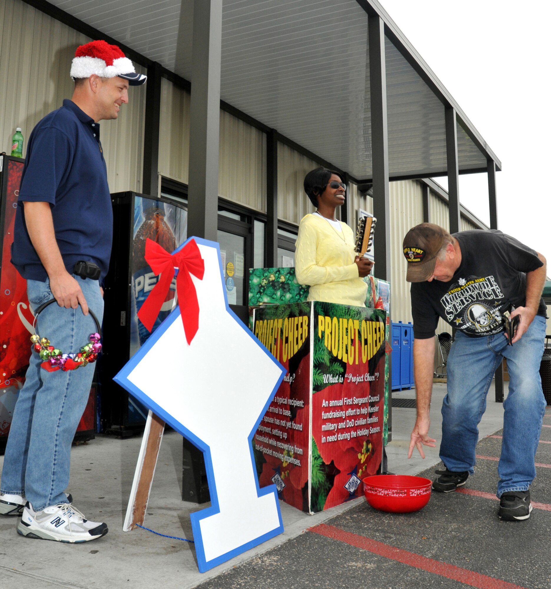Master Sgt. Robert Worley, left, and Staff Sgt. Stephanie Meda, 334th Training Squa-dron, ring the bells outside the base exchange Friday to collect donations for Project Cheer as Army retiree James Willcockson makes a contribution.  (U.S. Air Force photo by Adam Bond)