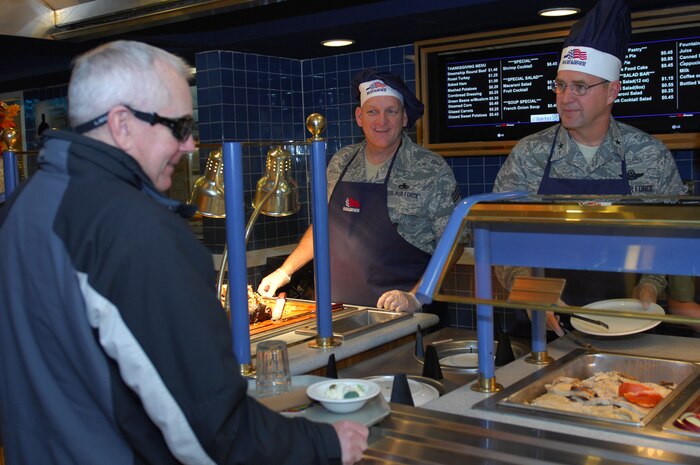 Brig. Gen. Stephen Hoog, United States Air Force Warfare Center commander, (right) and Chief Master Sgt. Jack Adams, 57th Wing command chief, serve Thanksgiving dinner to a member of the Nellis community at the Mountain View Dining Facility November 27, 2008.  Every year the 99th Services Squadron provides the men, women and families of Nellis Air Force Base with a traditional Thanksgiving dinner served by the base leadership. (U.S Air Force photo/ Staff Sgt. Taylor Worley)