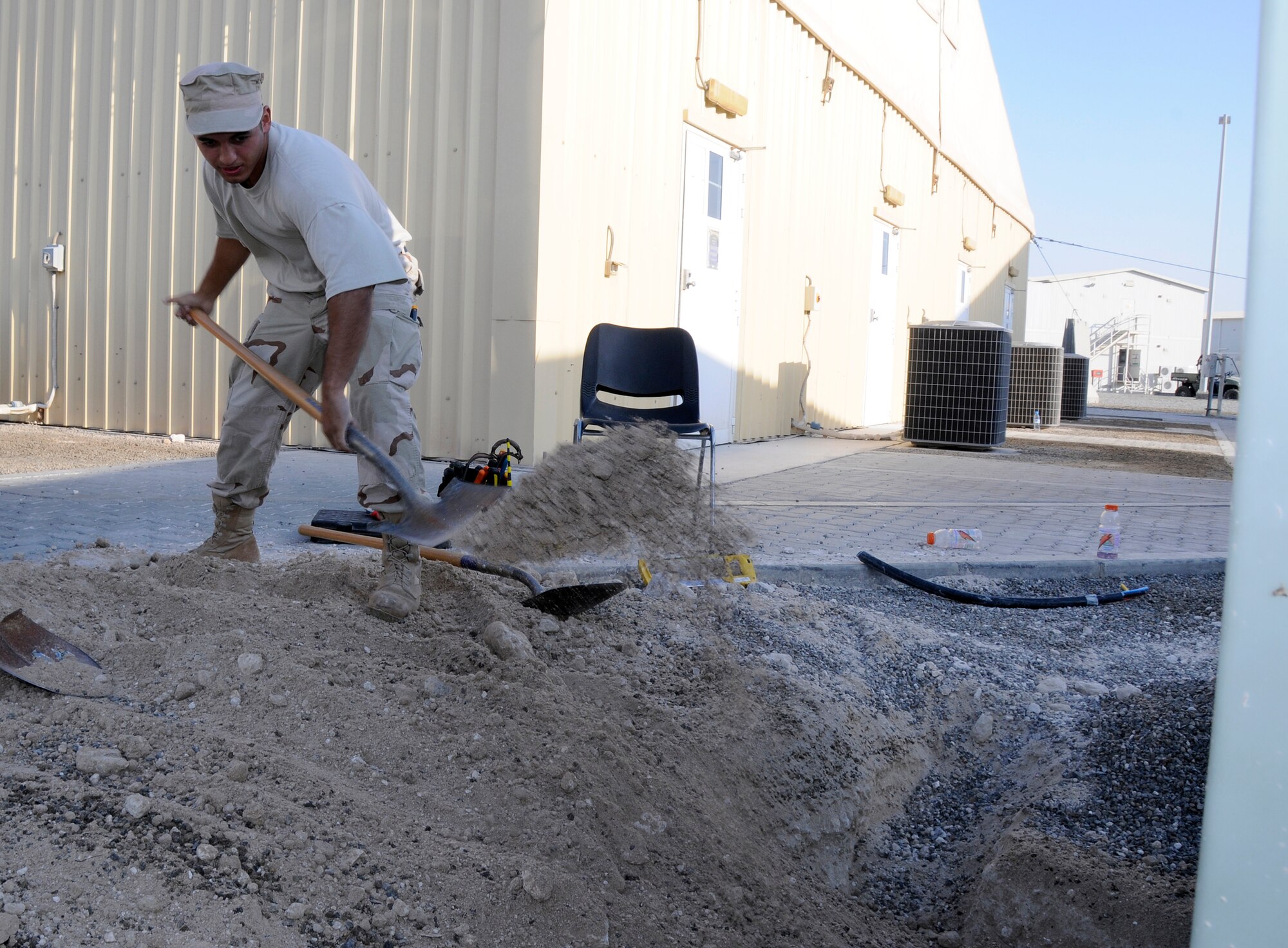 SOUTHWEST ASIA -- Airman 1st Class Carlos Suarez from the 380th Expeditionary Civil Engineer Squadron shovels final grade here Nov. 25. He is replacing the dirt from a trench dug to get to feeder circuits. The electric shop had to get to the circuits to provide electricity to a new ECS building. Airman Suarez is deployed from the 735th CES Ramstein Air Base, Germany; his hometown is Honolulu, Hawaii. (U.S. Air Force photo/Tech. Sgt. Christopher A. Campbell)(released)