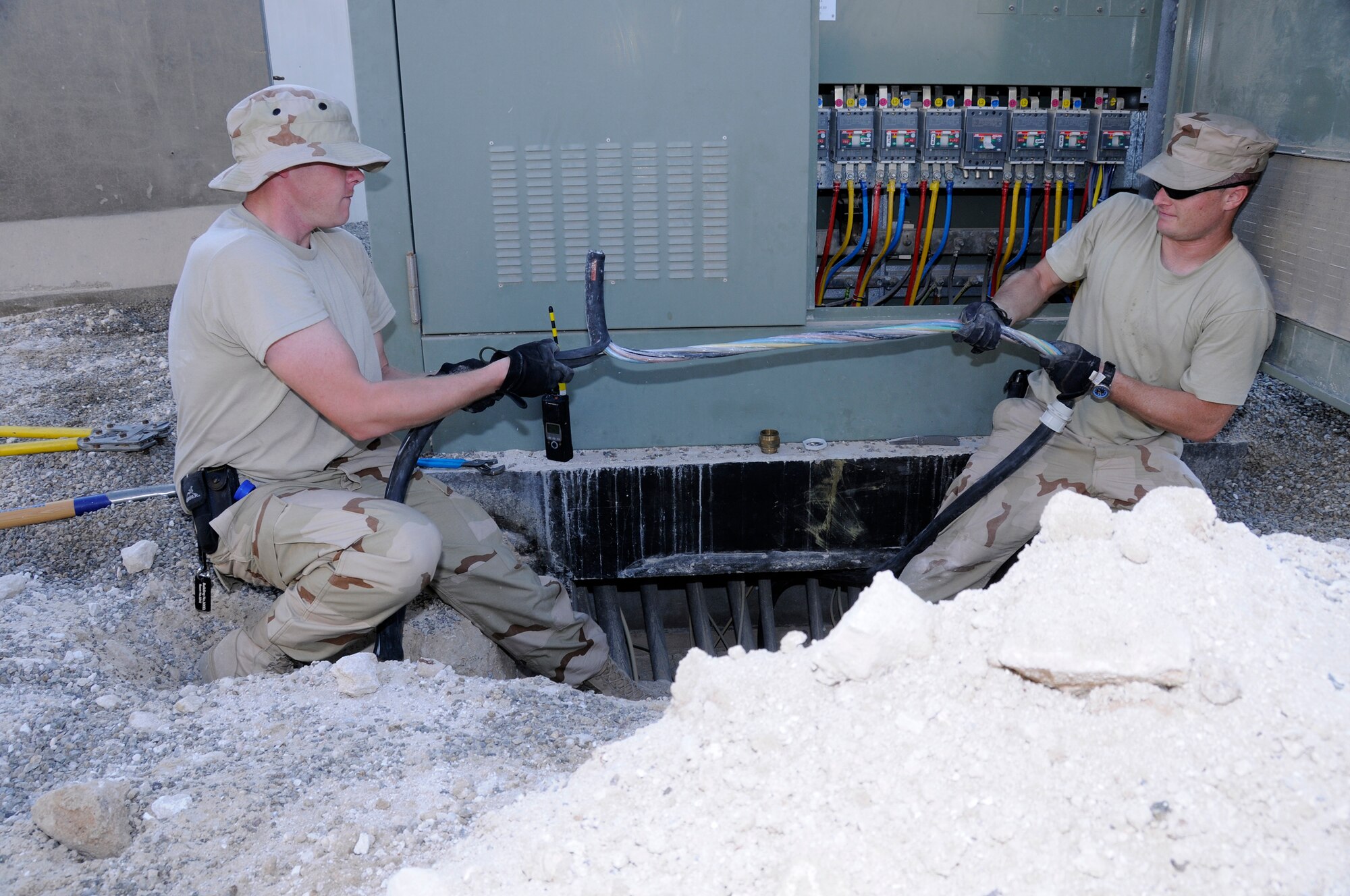SOUTHWEST ASIA -- Staff Sgt. Phillip Feldcamp and Staff Sgt. Wayne Byrd from the 380th Expeditionary Civil Engineer Squadron strip a power cable here Nov. 25. The cable is going to feeder circuits to provide a new ECES building with electricity. Sergeant Byrd is deployed from the 735th CES Ramstein Air Base, Germany, his hometown is Casa Grande, Ariz.  Sergeant Feldcamp, a native of Louisville, Ky., is deployed out of Sheppard Air Force Base, Texas. (U.S. Air Force photo/Tech. Sgt. Christopher A. Campbell)(released)