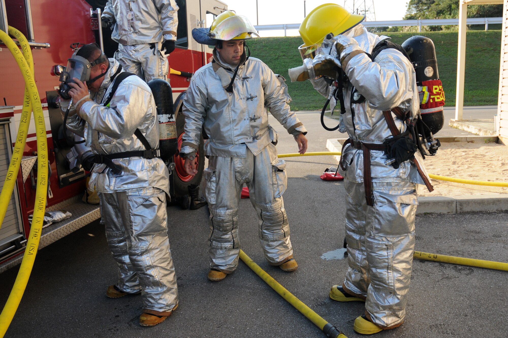Staff Sgt. John Garcia (left), Airmen 1st Class David Moncayo (center) and Vincent Kinard, all from the 18th Civil Engineering Squadron Fire Department, remove their gear after putting out a simulated kitchen fire at the Silver Flag Training Facility Dec. 2 at Kadena Air Base. The 18th Wing is participating in a Local Operational Readiness Exercise to test the readiness of Kadena Airmen.(U.S. Air Force photo/Airman 1st Class Amanda Grabiec)