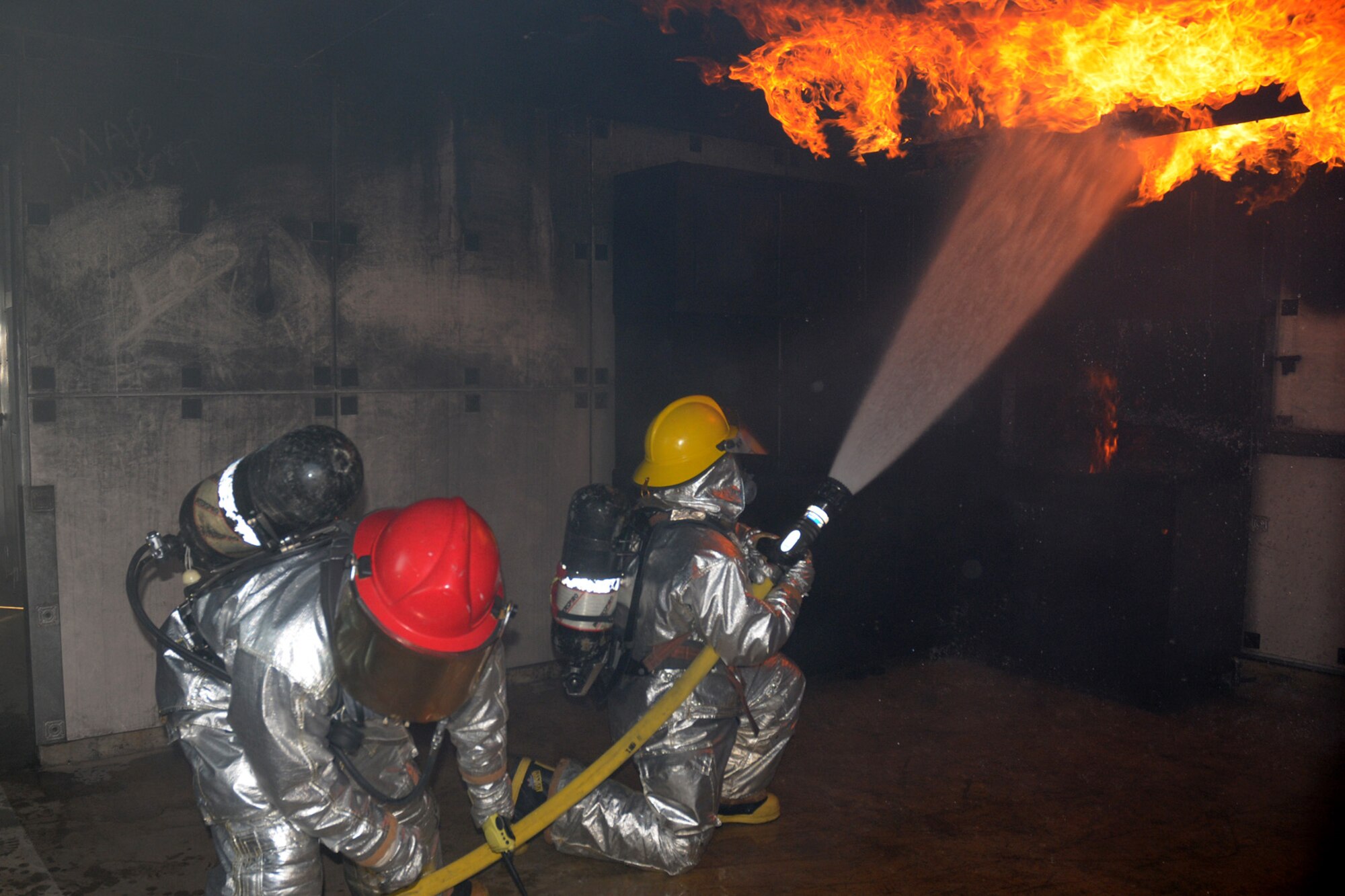 Staff Sgt. John Garcia (right) and Airman 1st Class Vincent Kinard, 18th Civil Engineering Squadron Fire Department, work together to put out the flames in a simulated kitchen fire at the Silver Flag Training Facility Dec. 2 at Kadena Air Base. The 18th Wing is participating in a Local Operational Readiness Exercise to test the readiness of Kadena Airmen.(U.S. Air Force photo/Airman 1st Class Amanda Grabiec)