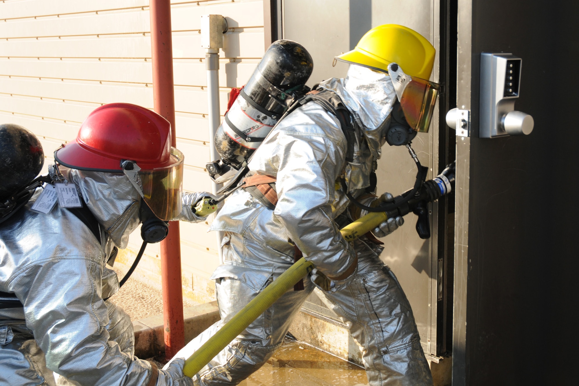 Airman 1st Class Vincent Kinard (front) and Staff Sgt. John Garcia, 18th Civil Engineering Squadron Fire Department, enter a building during a simulated kitchen fire scenario at the Silver Flag Training Facility Dec. 2 at Kadena Air Base. The 18th Wing is participating in a Local Operational Readiness Exercise to test the readiness of Kadena Airmen. (U.S. Air Force photo/Airman 1st Class Amanda Grabiec)