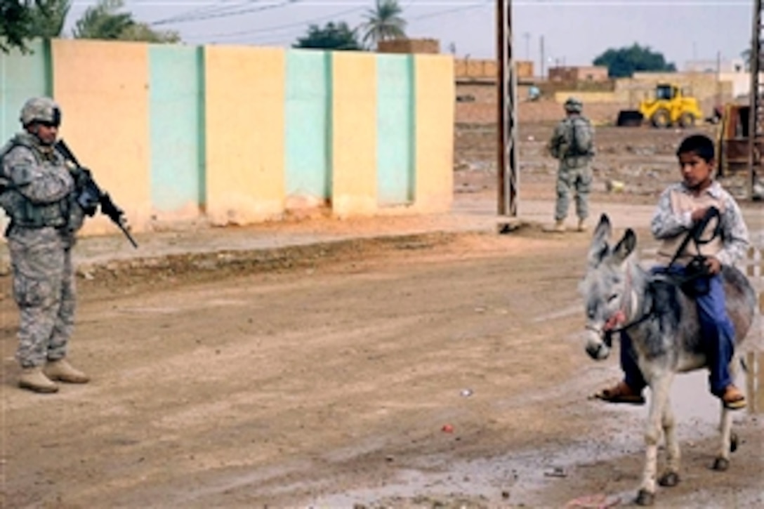 U.S. Army Staff Sgt. Raymond Ramos, providing security on a cordon and knock operation in Afak, Iraq, watches as an Iraqi boy passes by riding on a donkey, Nov. 30, 2008. Ramos is assigned to the 4th Infantry Division's 2nd Battalion, 8th Infantry Regiment, 2nd Brigade Combat Team.