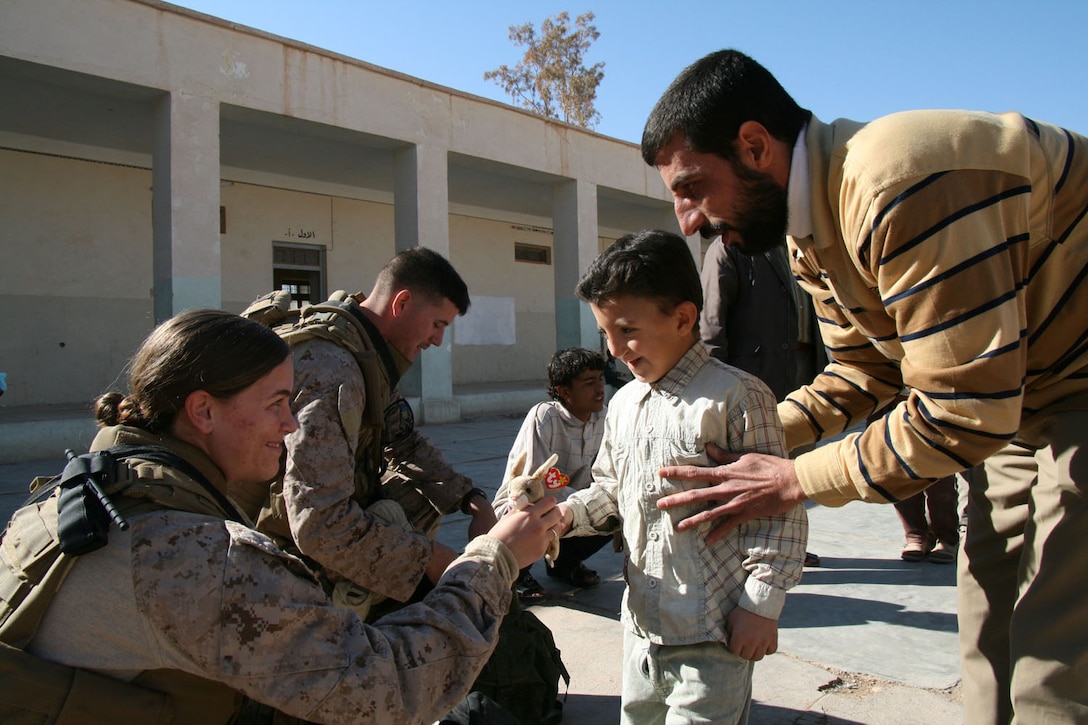 Petty Officer 2nd Class Bridget Shanahan, a corpsman with Shock Trauma Platoon, 2nd Combat Logistics Battalion, and Lance Cpl. Michael Johnson, a wireman with Communications Platoon, Headquarters and Service Company, 2nd Battalion, 25th Marine Regiment, Regimental Combat Team 5, hand out stuffed animals to a second grade student at Houran Primary School in Rutbah, Iraq, Dec. 2.  Not only was this the first time most of the children at Houran had ever interacted with Coalition forces, but it was an education in the integral role that females serve in the U.S. military.::r::::n::