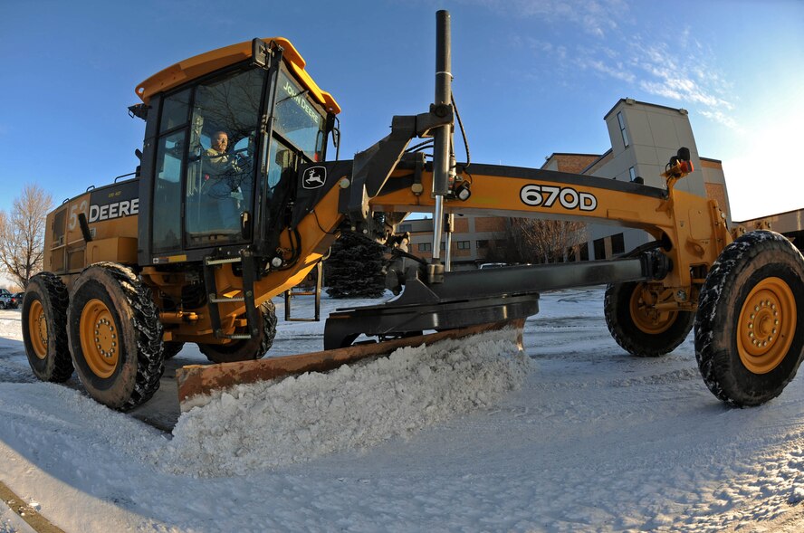 A snow plow clears the 28th Medical Group building parking lot here, Dec. 3.Tractors, four-wheelers, and trucks were equipped with plow blades in order to clear the snow and ice from the roads on Ellsworth. (US Air Force photo/Airman Corey Hook)