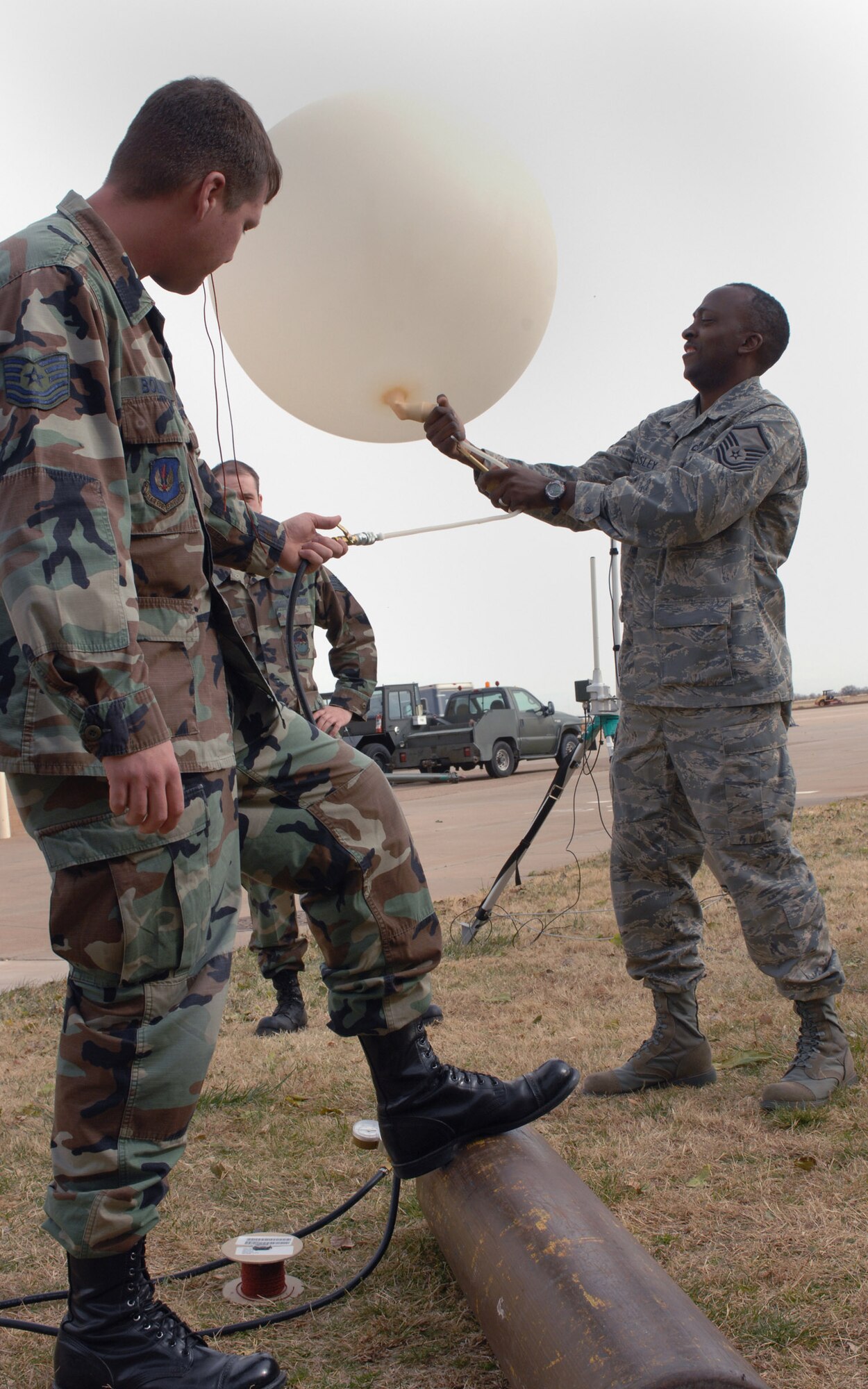 CANNON AIR FORCE BASE, N.M. ? Tech. Sgt. Adam Bolen, 27th Special Operations Support Squadron, adjusts the helium being blown into the weather balloon held by Master Sgt. Antonio Pressley, 27th SOSS, at Base Operations Dec. 2.  No oil can touch the balloon as it is being inflated or it with have a higher chance of blowing up before reaching appropriate altitudes.  (U.S. Air Force photo Airman 1st Class James R. Bell)