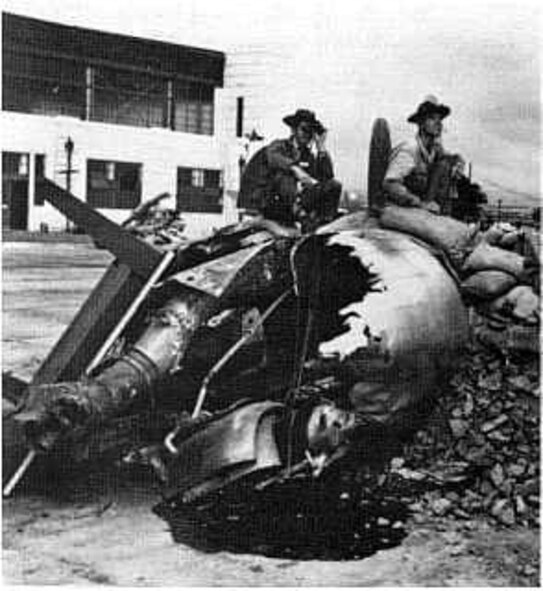 HICKAM AIR FORCE BASE, Hawaii -- Pfc. Raymond Perry and Cpl. Howard Marquardt of South Dakota man a gun emplacement, which was hastily constructed in front of Hangar 5 after the raid. A burned-out aircraft engine, sand bags, table and debris from the attack made up the construction material for this bunker. (PACAF History Office photo)
