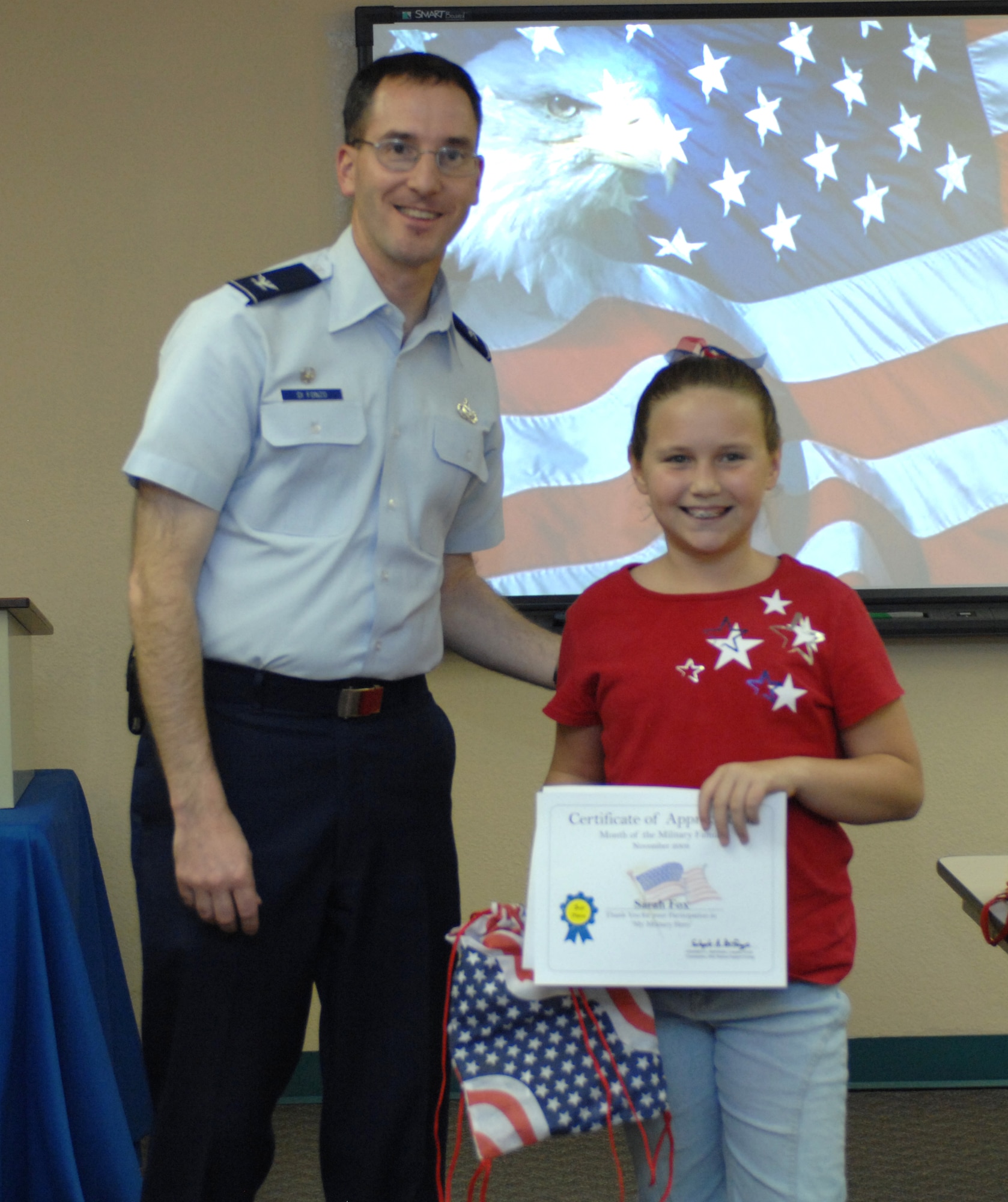 Col. Stephen DiFonzo, 49th Mission Support Group commander, presents an award to Sarah Fox for winning 3rd place in the 7 - 12 year old category of the drawing contest at the Airman and Family Readiness Center at Holloman Air Force Base, N.M., Nov. 24. The theme for the drawing contest was "My Military Hero" in support of Military Family Appreciation Month. (U.S. Air Force photo/Airman Sondra M. Escutia)