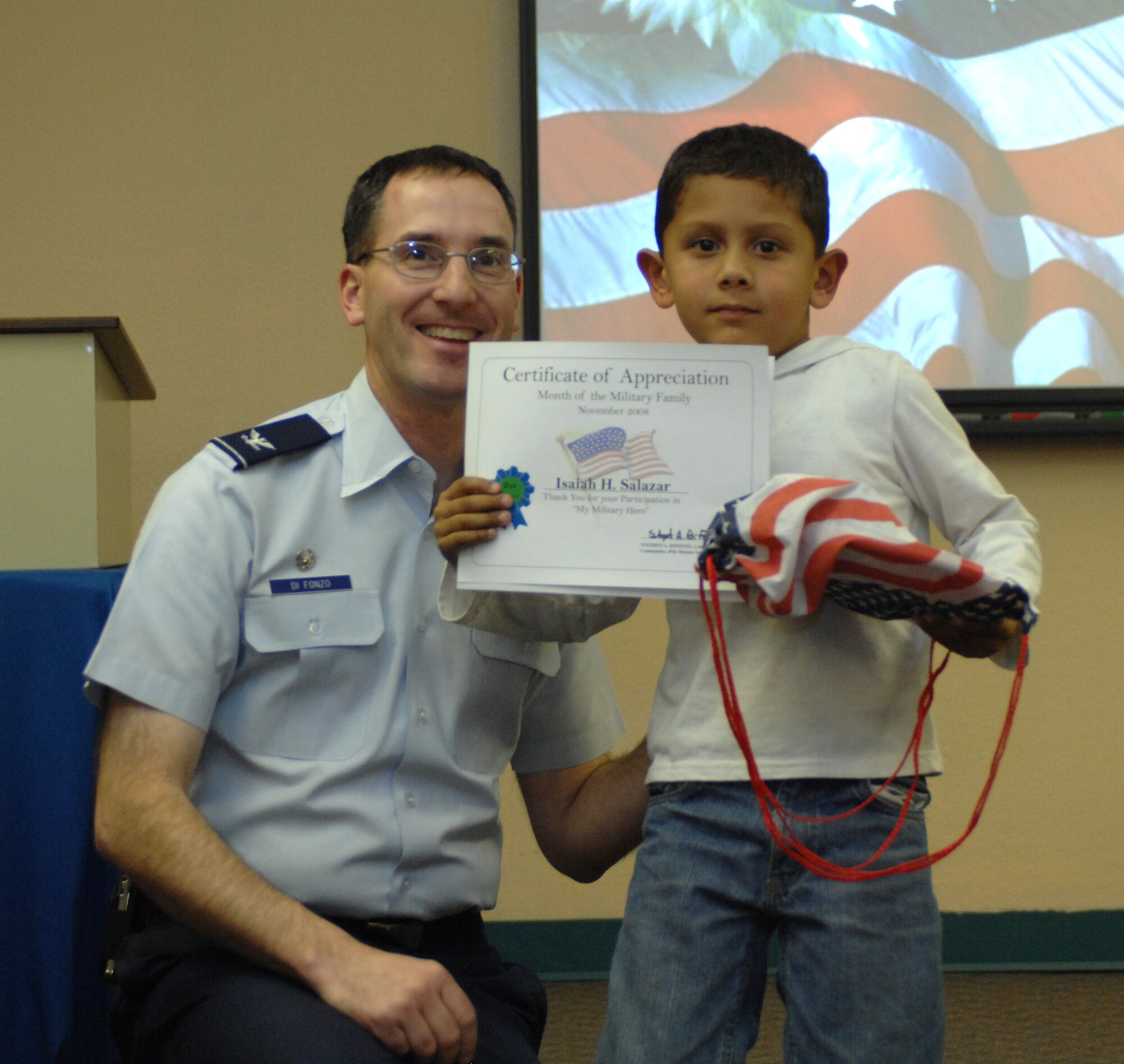 Col. Stephen DiFonzo, 49th Mission Support Group commander, presents an award to Isaiah Salazar for winning 2nd place in the 6 and under category of the drawing contest at the Airman and Family Readiness Center at Holloman Air Force Base, N.M., Nov. 24. The theme for the drawing contest was "My Military Hero" in support of Military Family Appreciation Month. (U.S. Air Force photo/Airman Sondra M. Escutia)