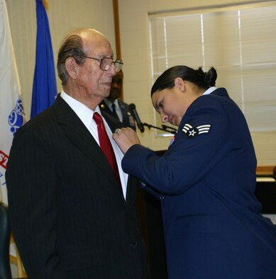 Senior Airman Crystal Garza proudly pins the Purple Heart on her grandfather, Mr. Hilario Riojas, during the official Purple Heart Ceremony in his honor November 26. 