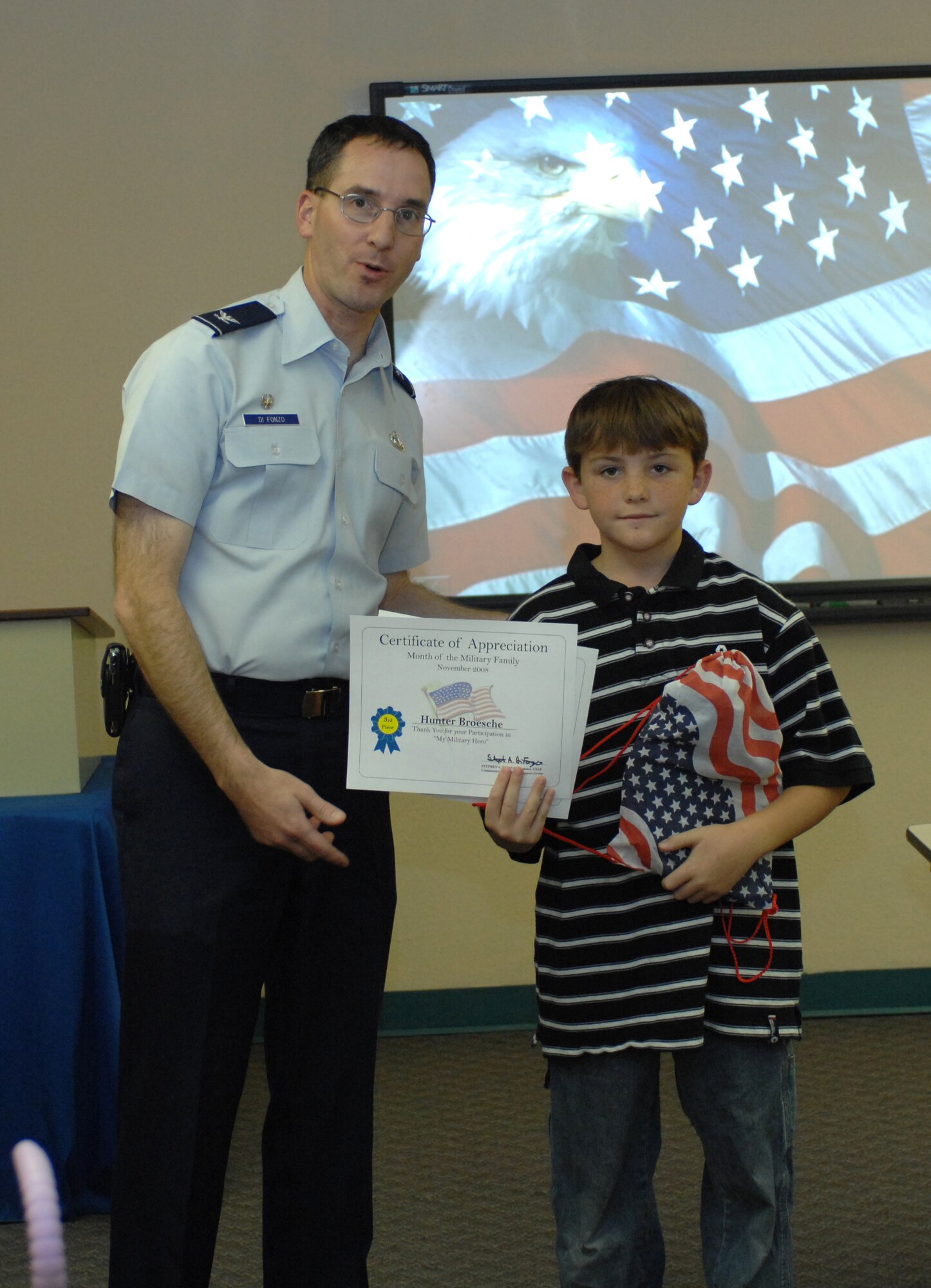 Col. Stephen DiFonzo, 49th Mission Support Group commander, presents an award to Hunter Broesche for winning 3rd place in the 7 - 12 year old category of the essay contest at the Airman and Family Readiness Center at Holloman Air Force Base, N.M., Nov. 24. The theme for the essay contest was "My Military Hero" in support of Military Family Appreciation Month. (U.S. Air Force photo/Airman Sondra M. Escutia)